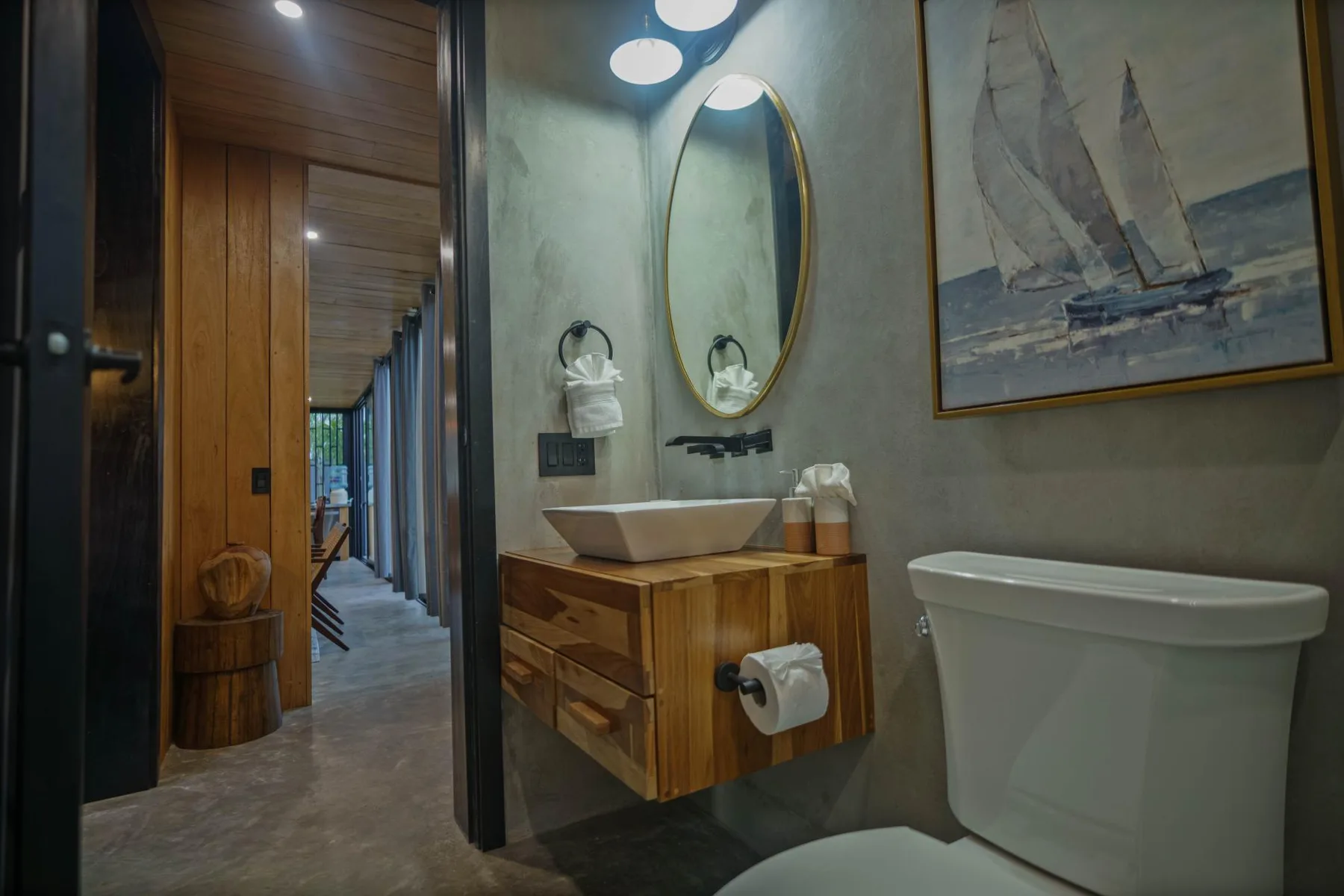A bathroom with a wooden vanity, oval mirror, and freestanding bathtub.