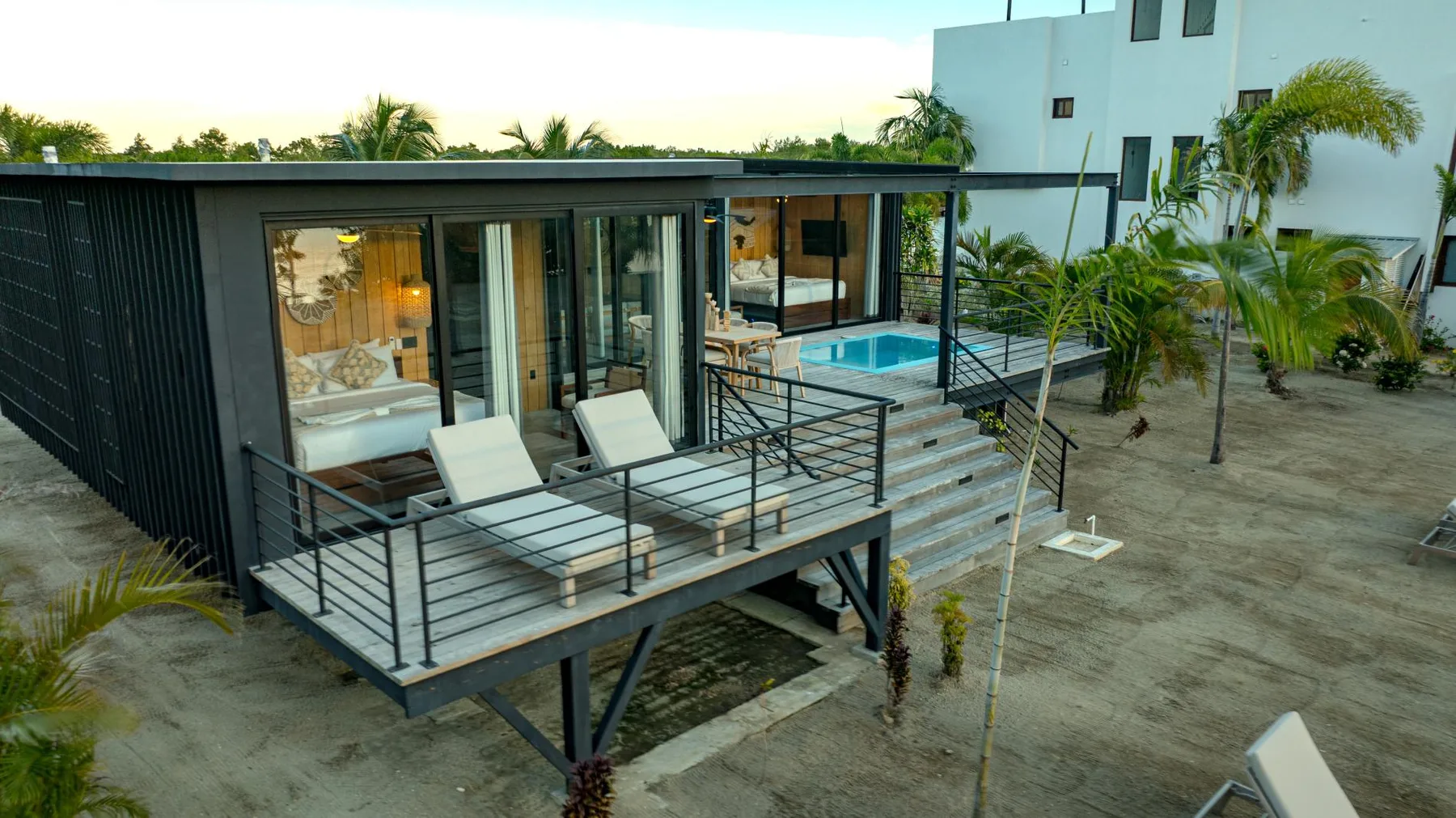 A modern building with a raised deck, outdoor seating, and a pool.