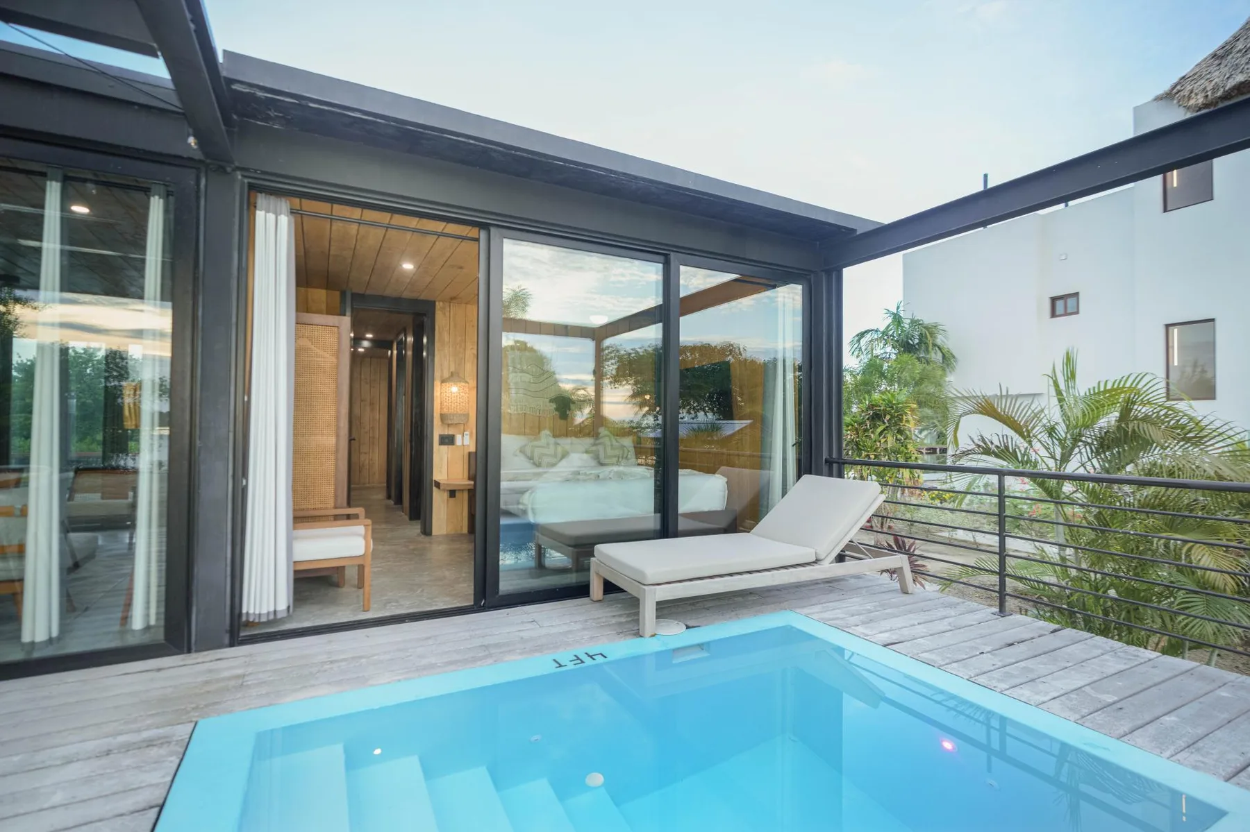 A swimming pool sits beside a glass-walled patio with lounge seating.