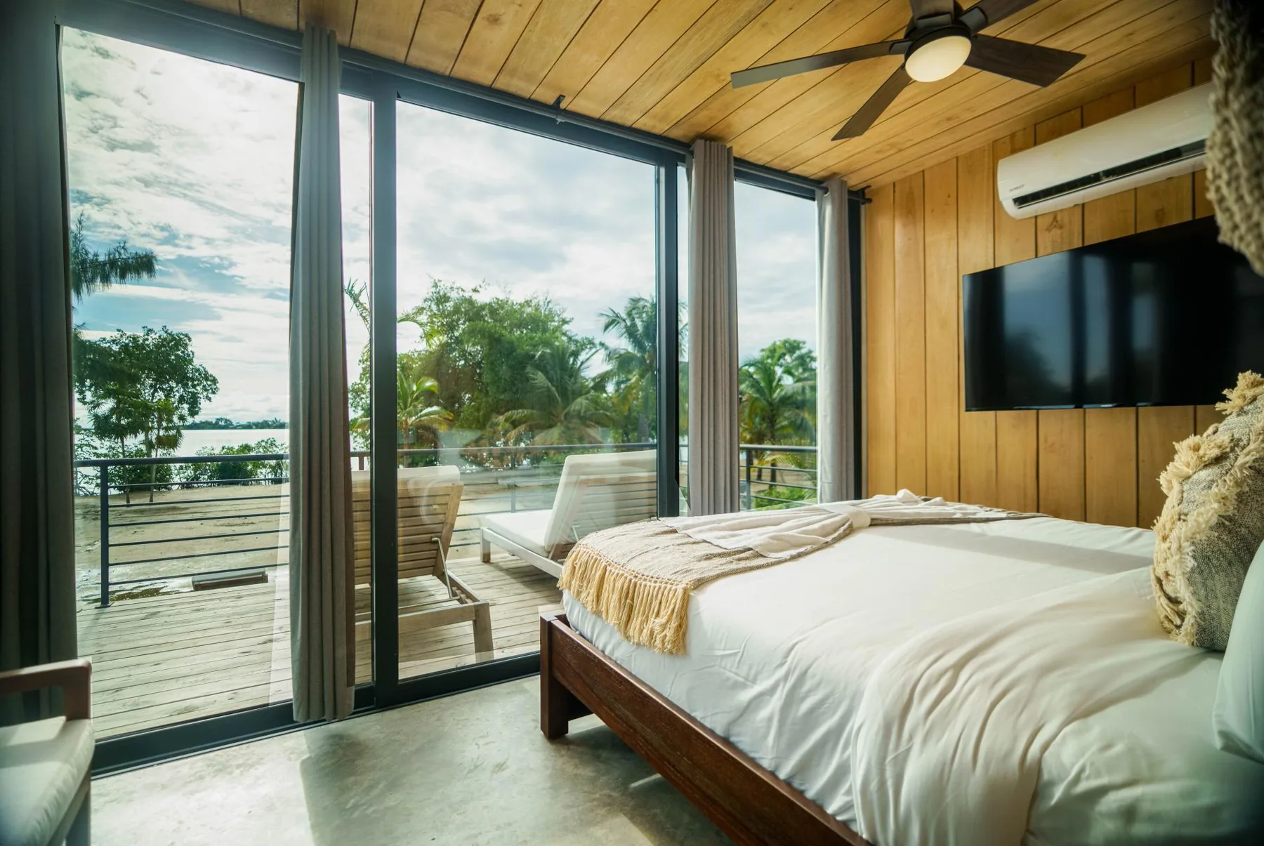 A bedroom with a bed beside large glass doors opening onto a deck.