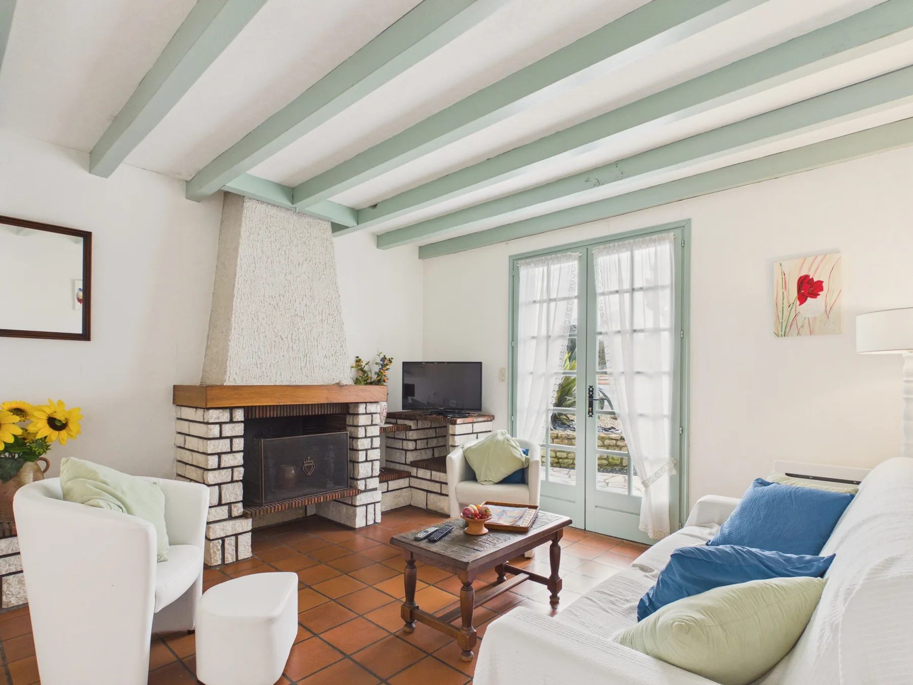 Living room with a fireplace, seating, and doors opening to a garden.