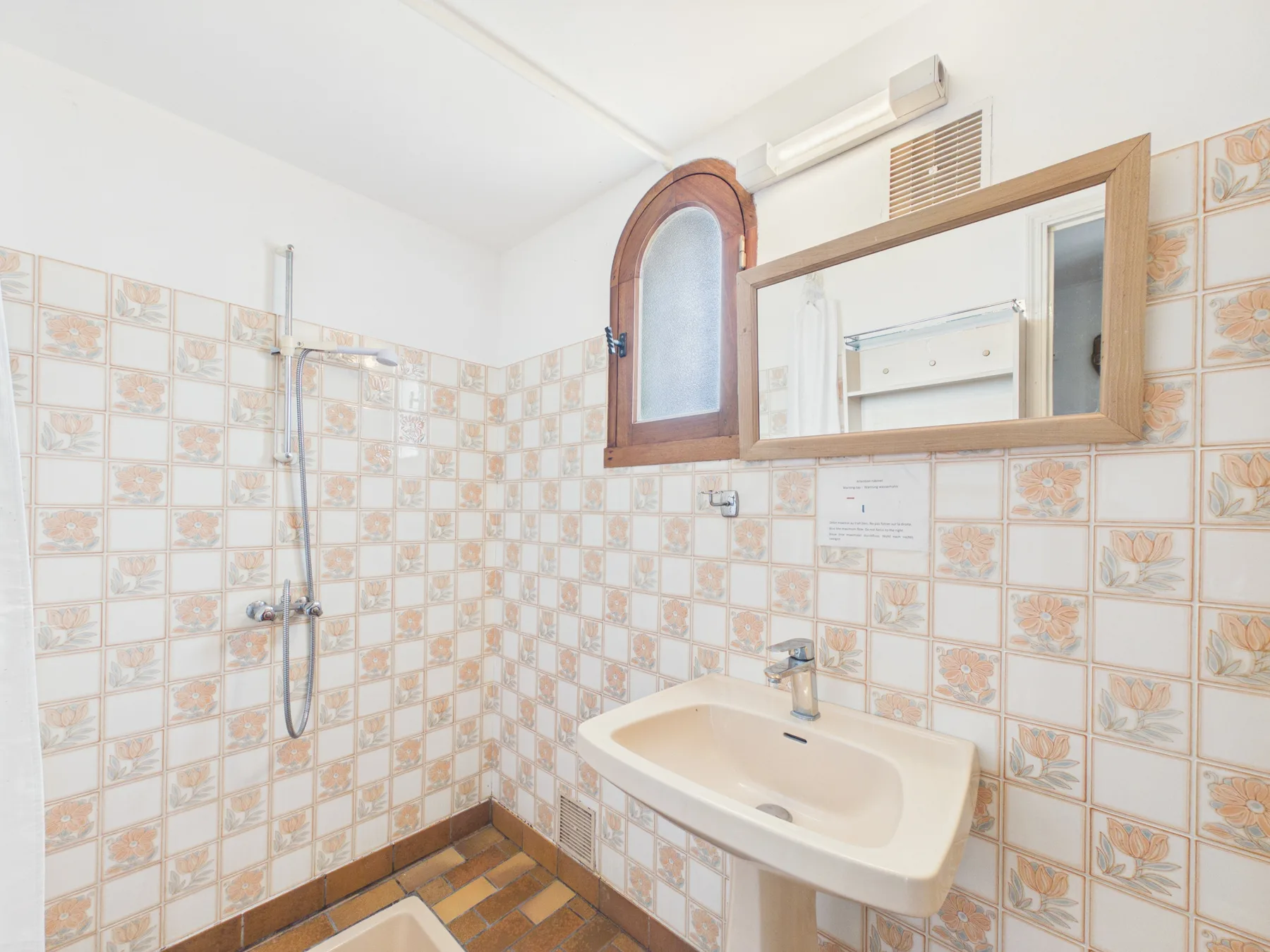 A tiled bathroom with a sink and wall mirror.