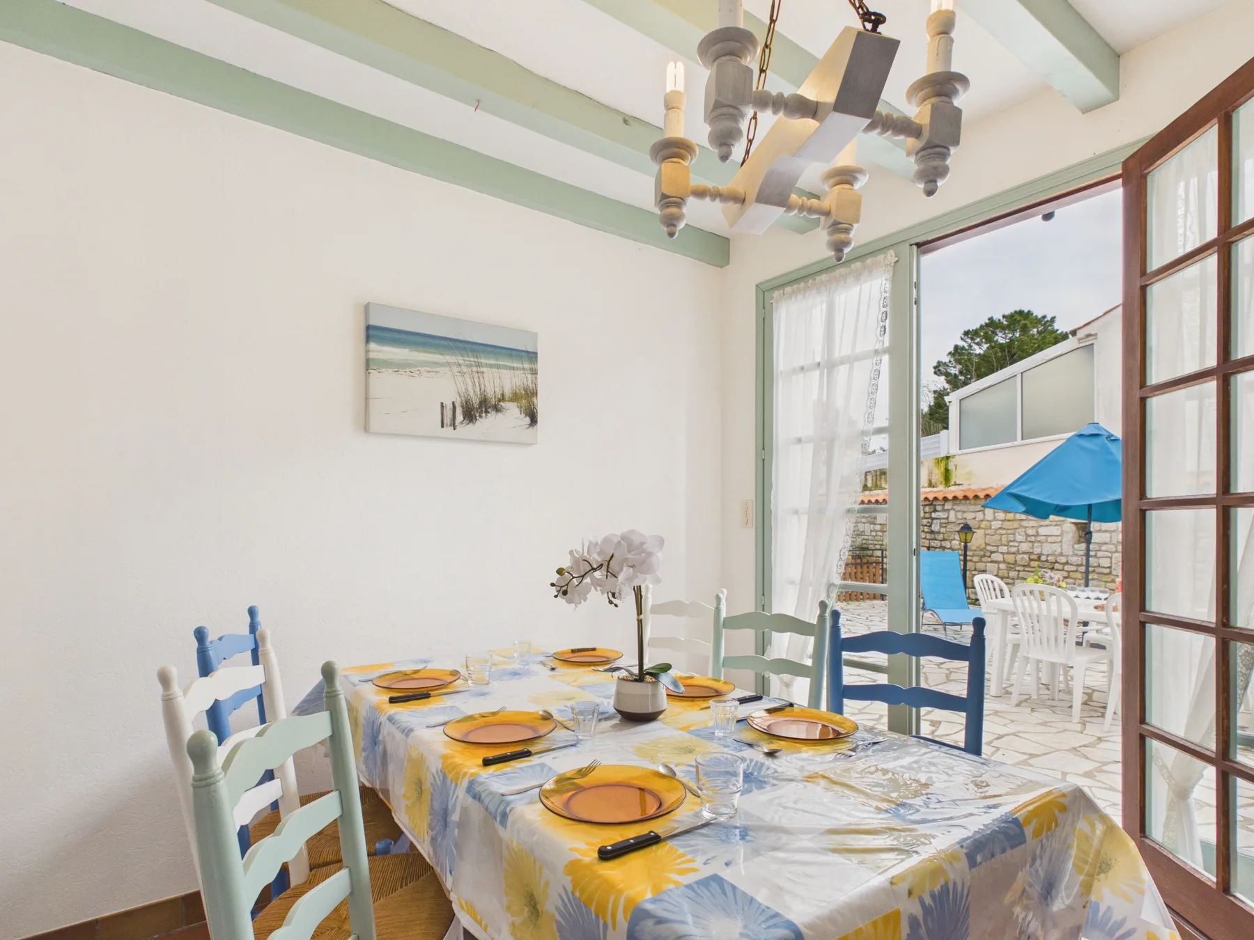 A dining area with a set table beside open doors to a patio.