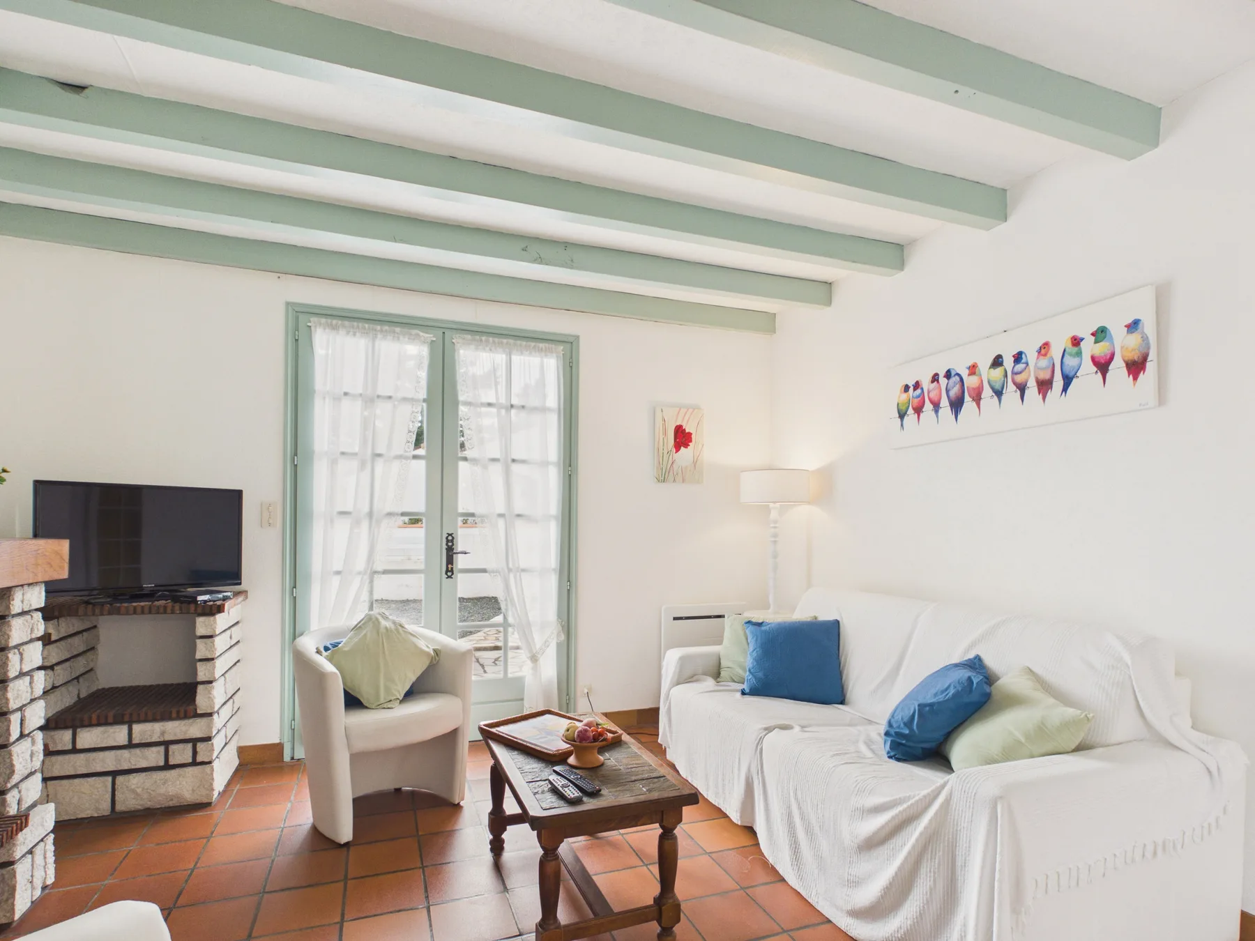 A bright living room with a white sofa, armchair, and wooden coffee table.