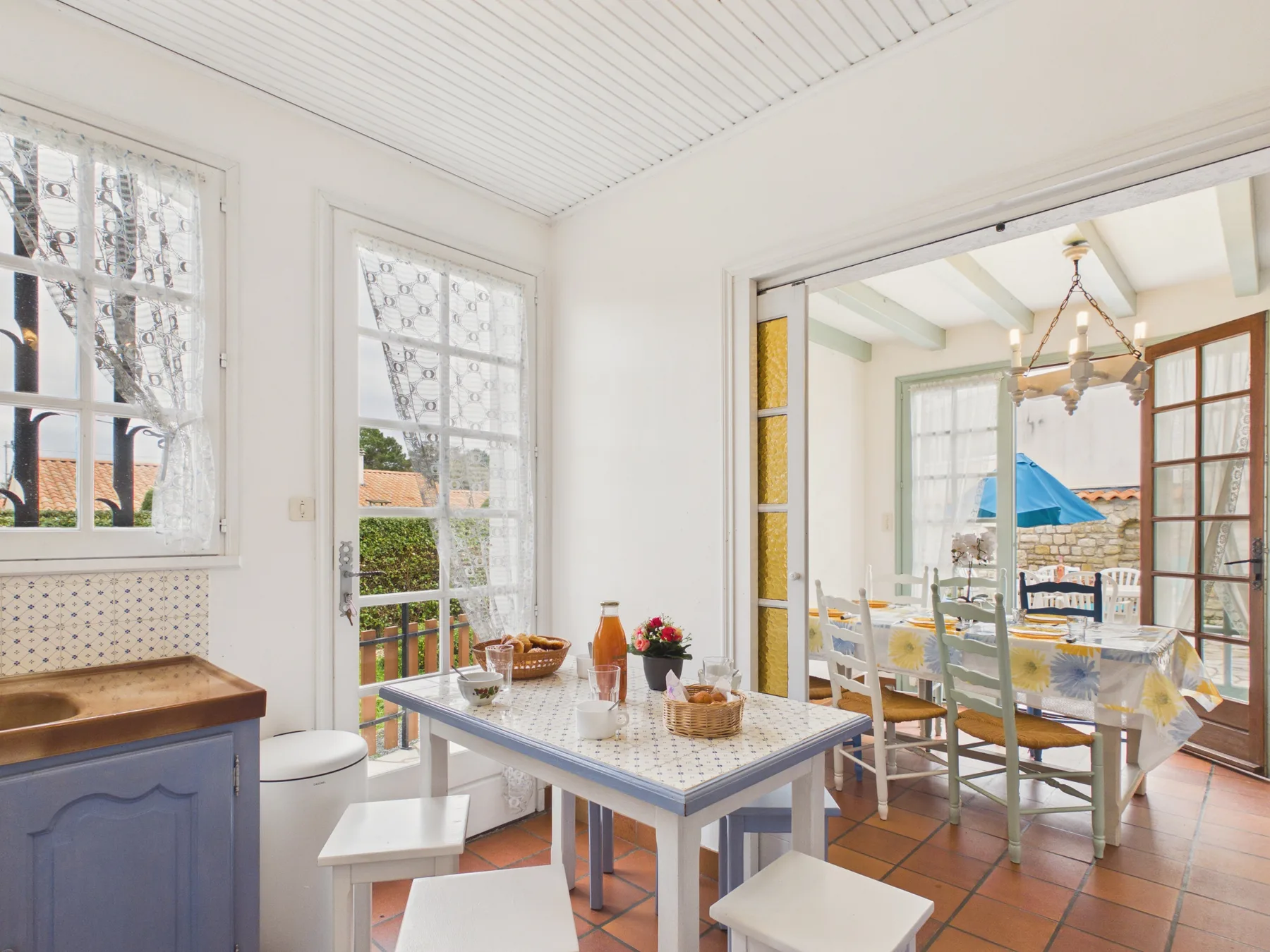 A bright dining area with a table and chairs beside open glass doors.