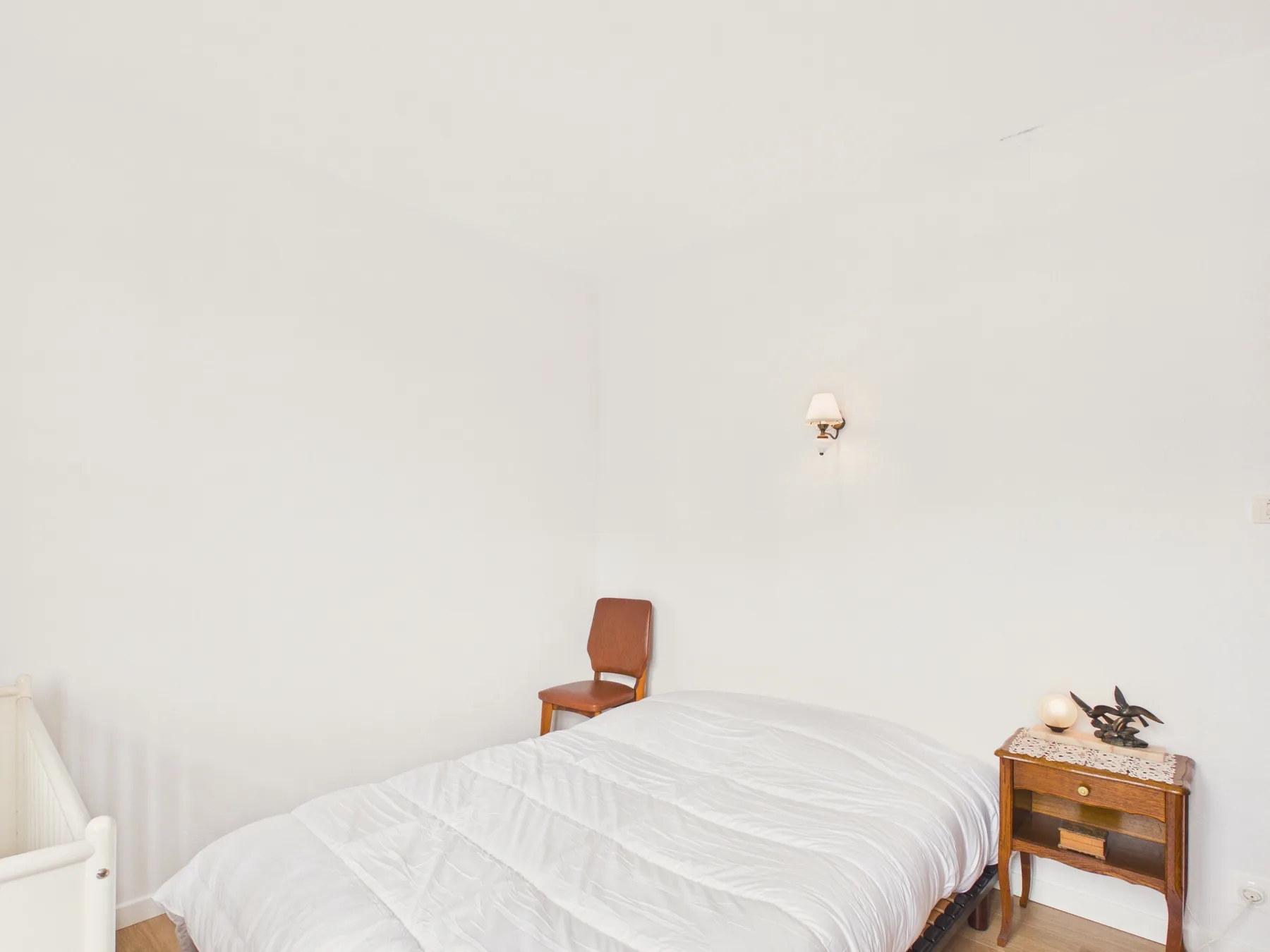 A bedroom with a bed and a small bedside table.