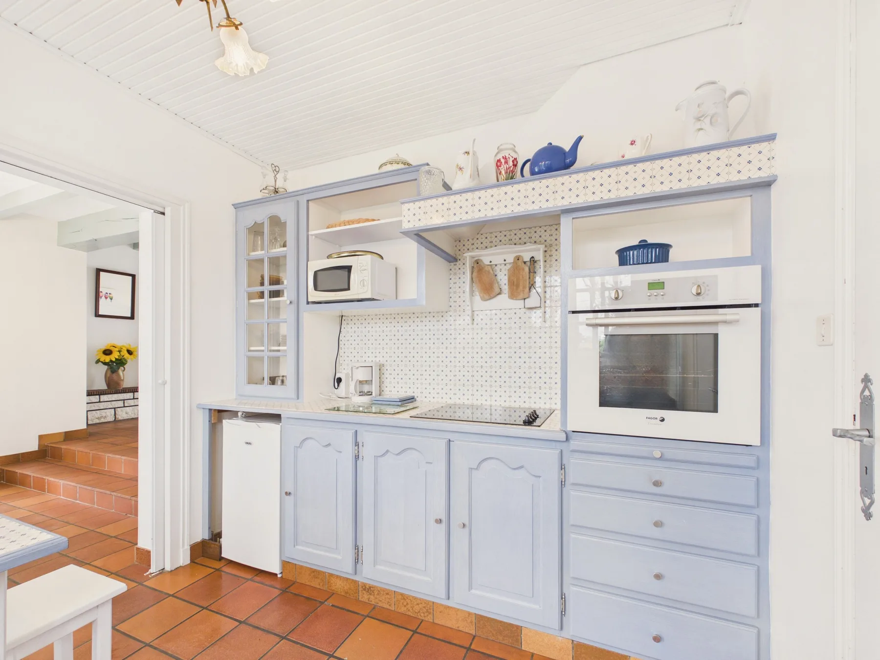A bright kitchen with pale blue cabinets, a microwave, and an oven.