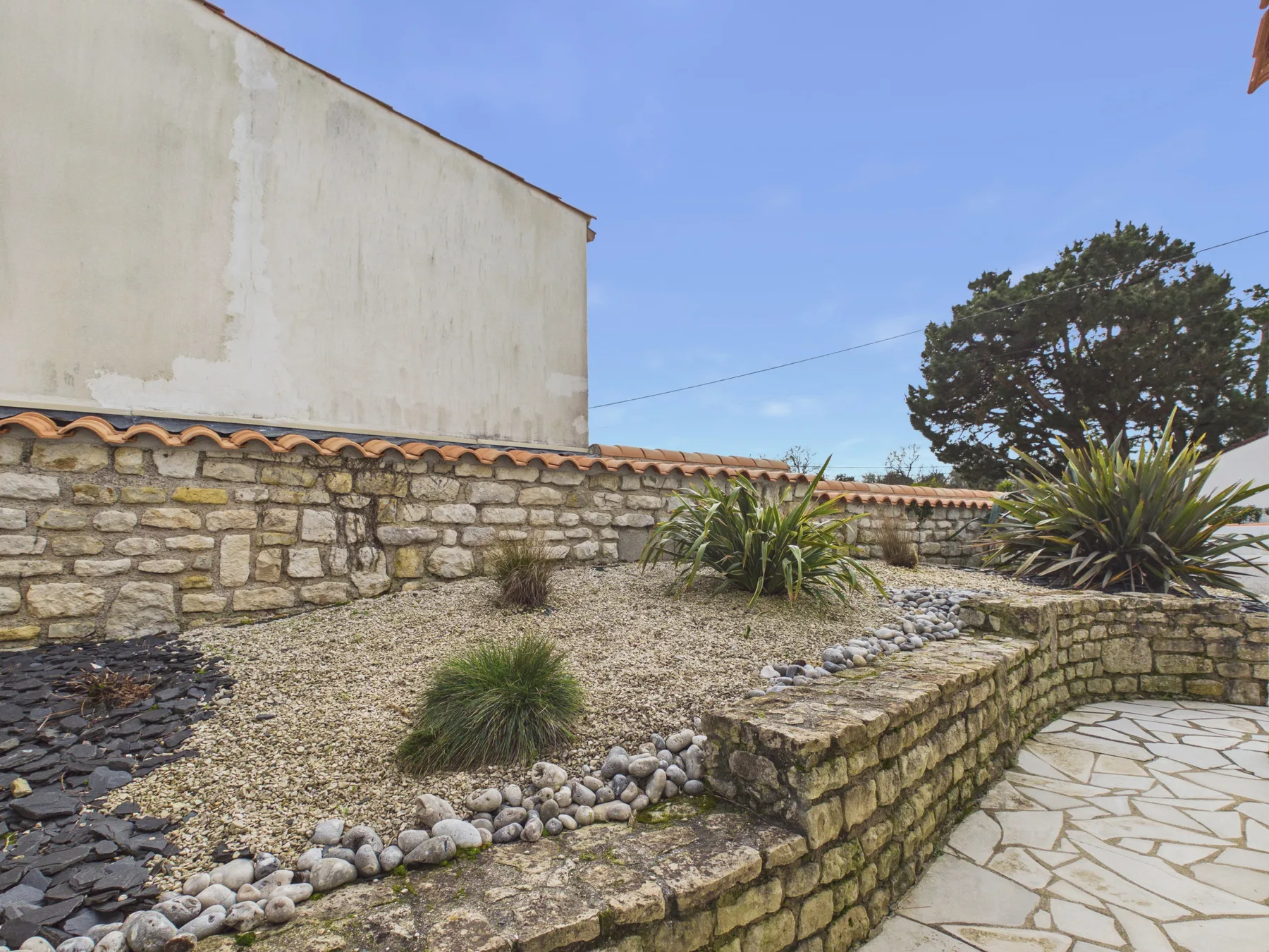 A stone courtyard garden with gravel beds and a paved walkway.