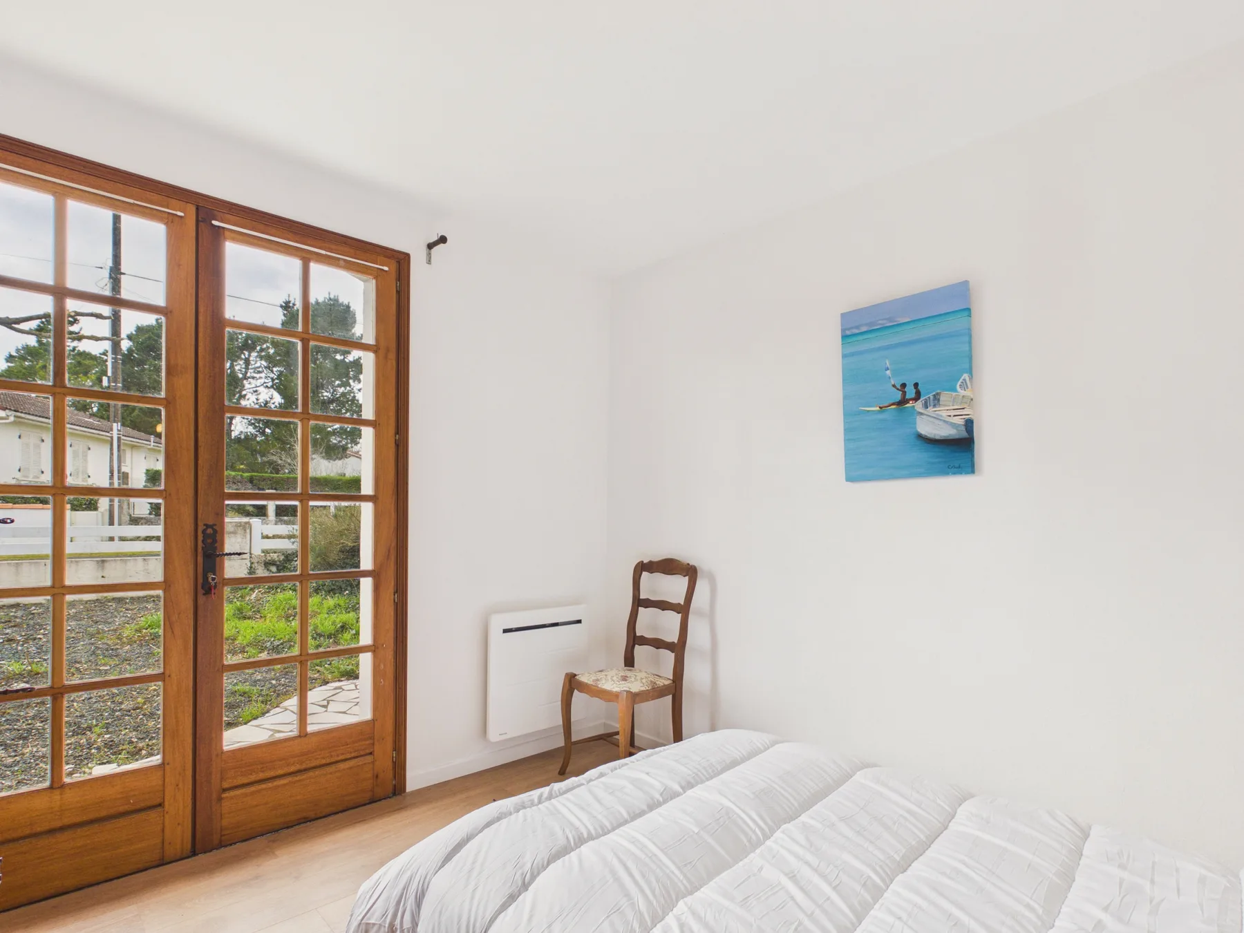 A bedroom with a bed beside wooden-framed glass doors.