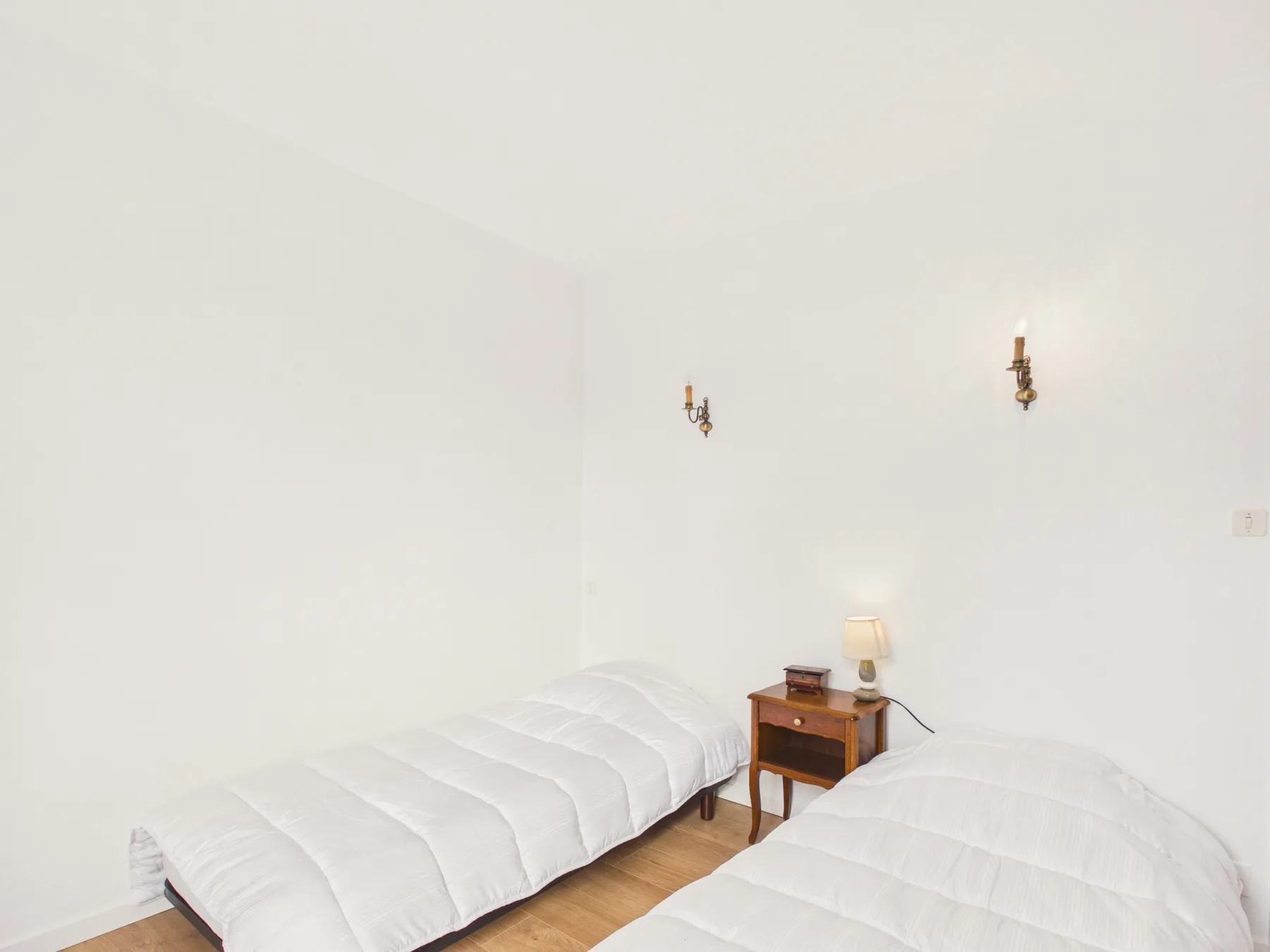 A bedroom with two beds and a small bedside table.