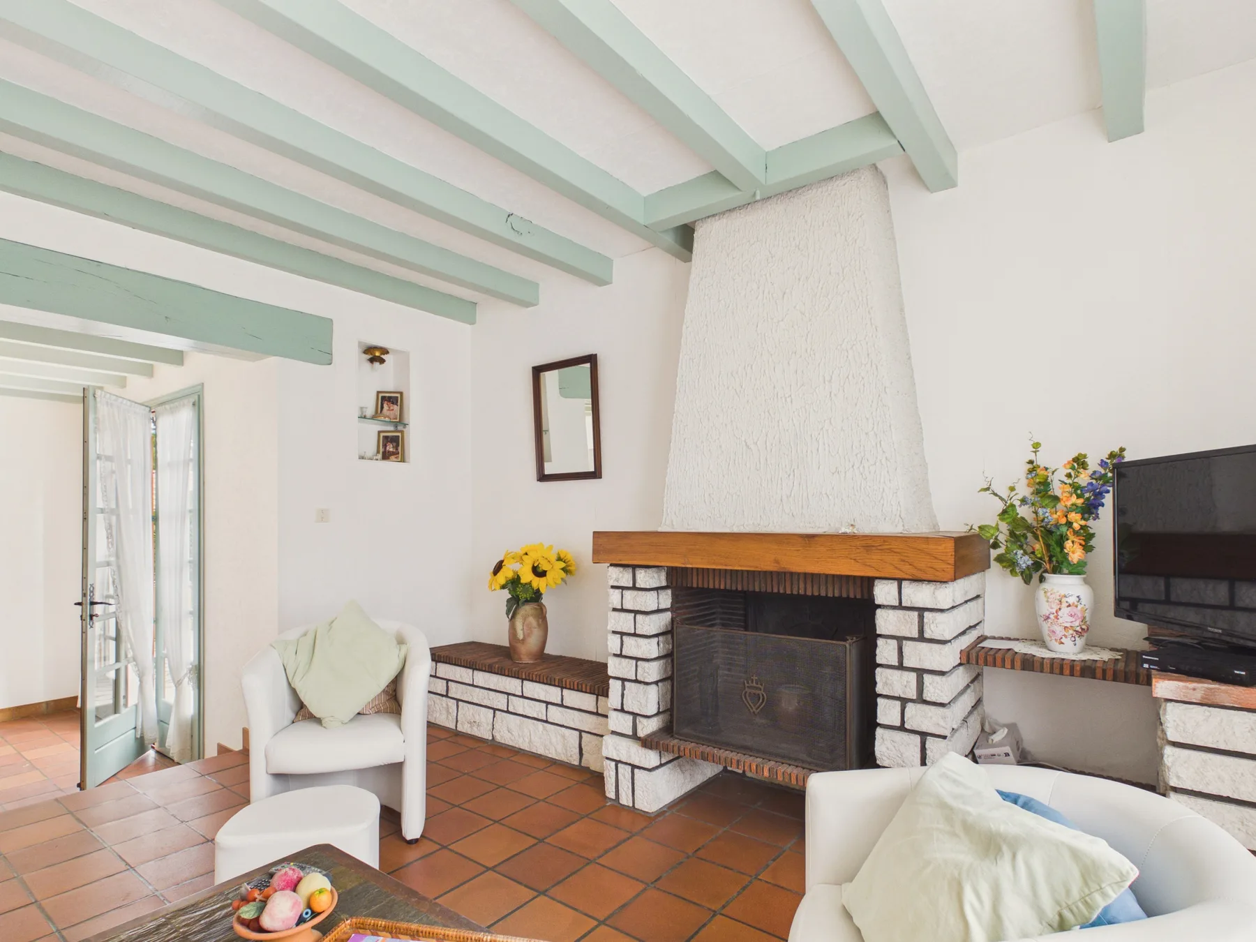 A living room with a brick fireplace and light-colored seating.