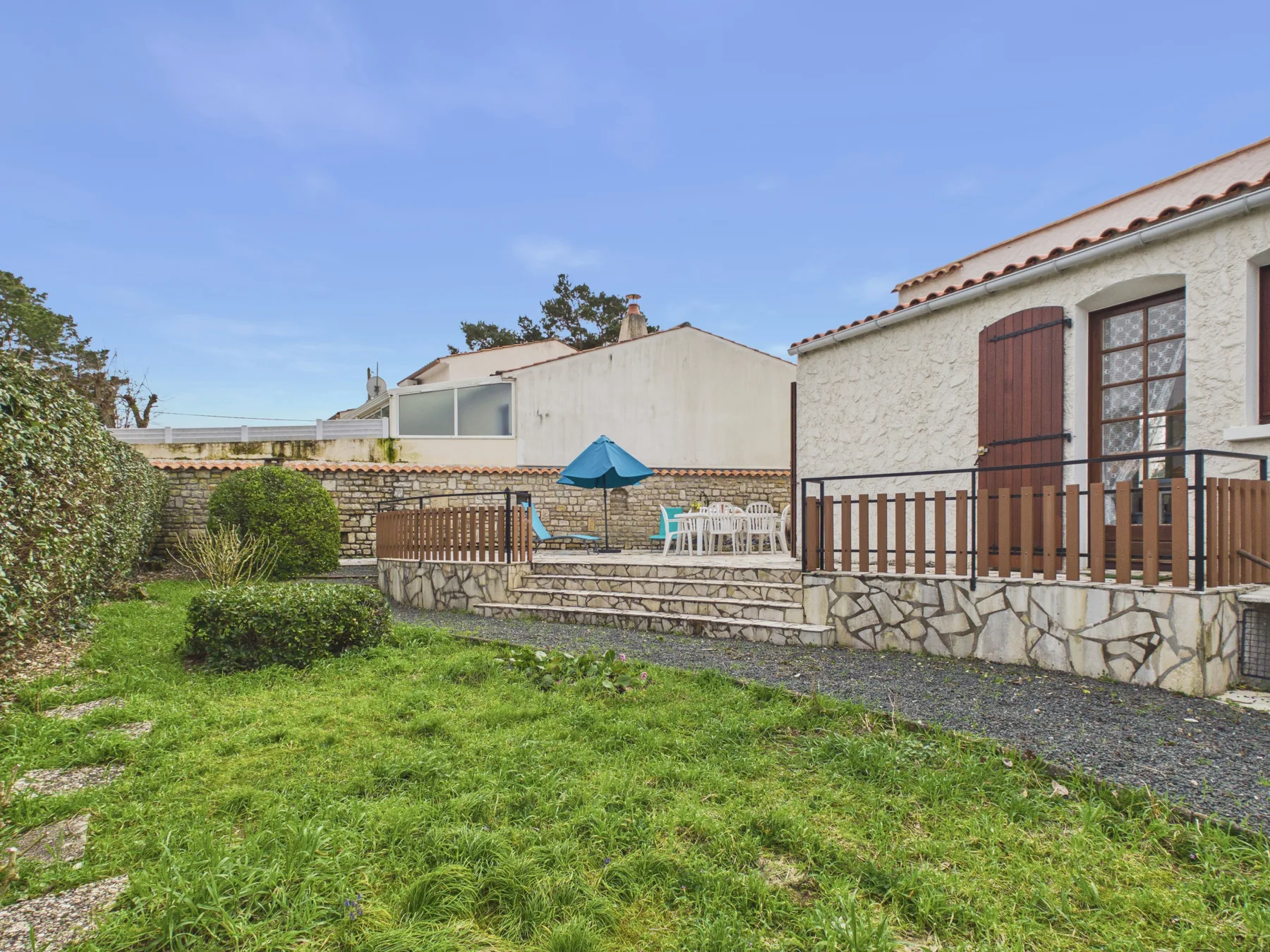 A grassy garden beside a stone house, with a patio seating area.