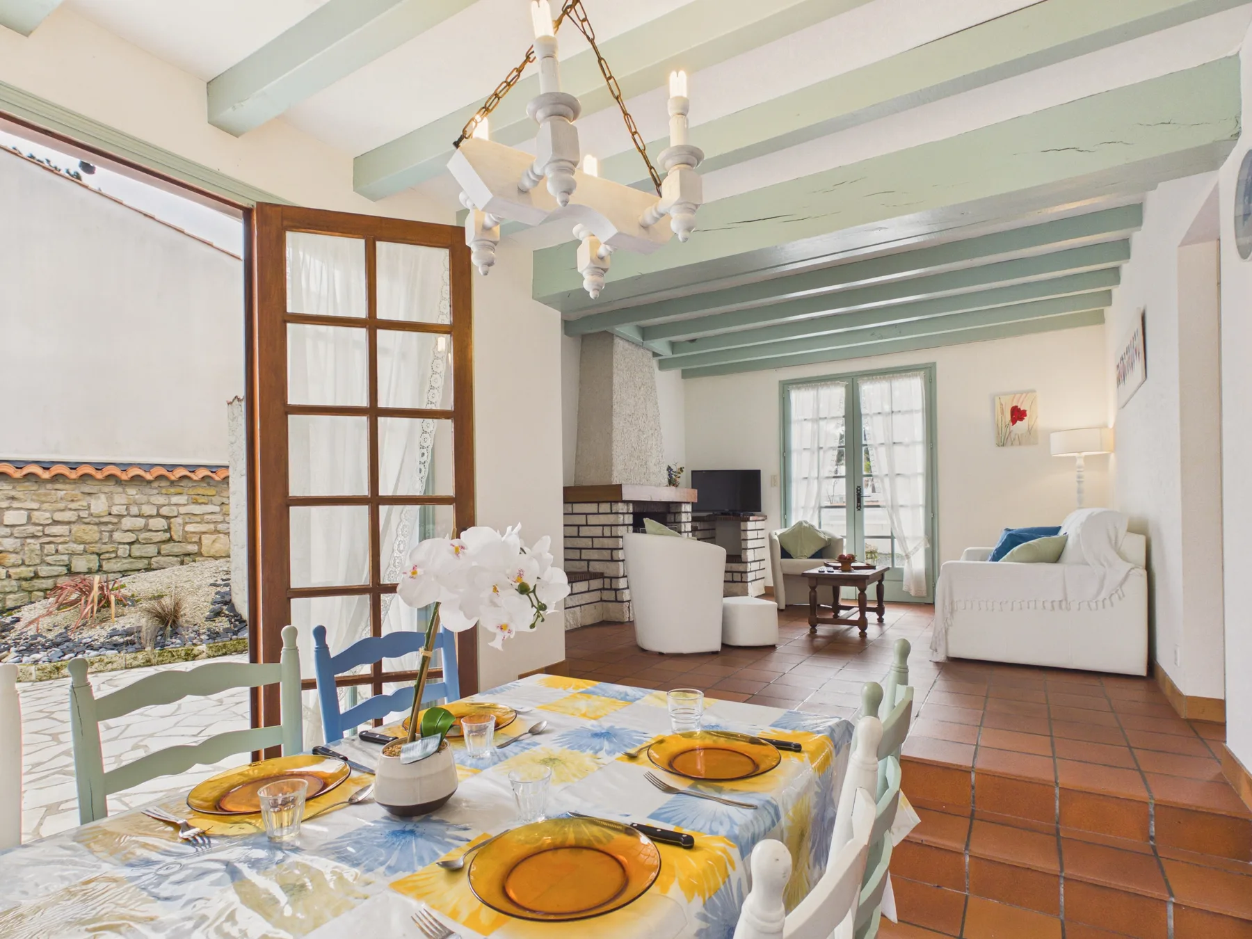 A dining area with a set table and seating beneath exposed ceiling beams.