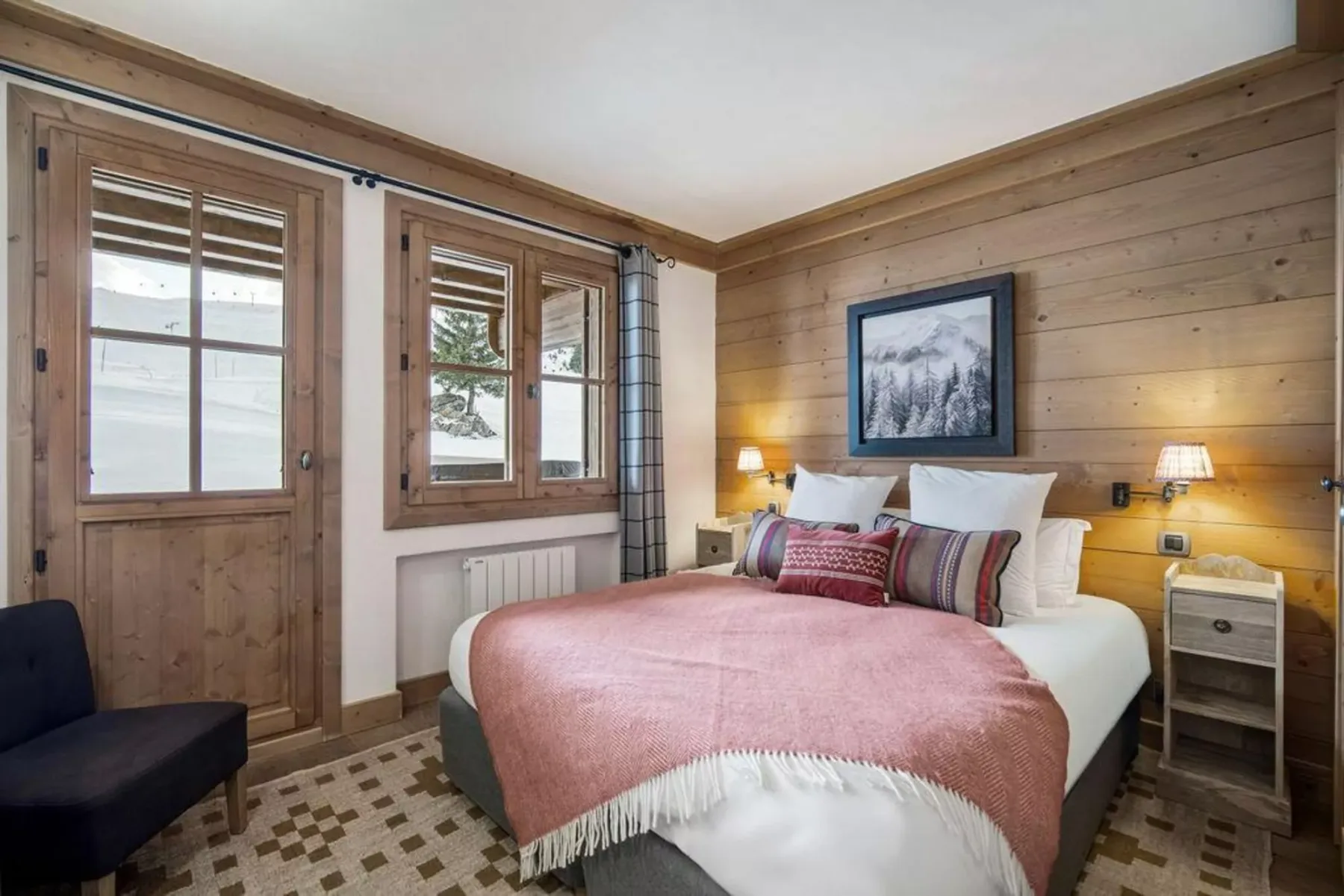 Bedroom with a bed dressed in pink bedding and wood-paneled walls.