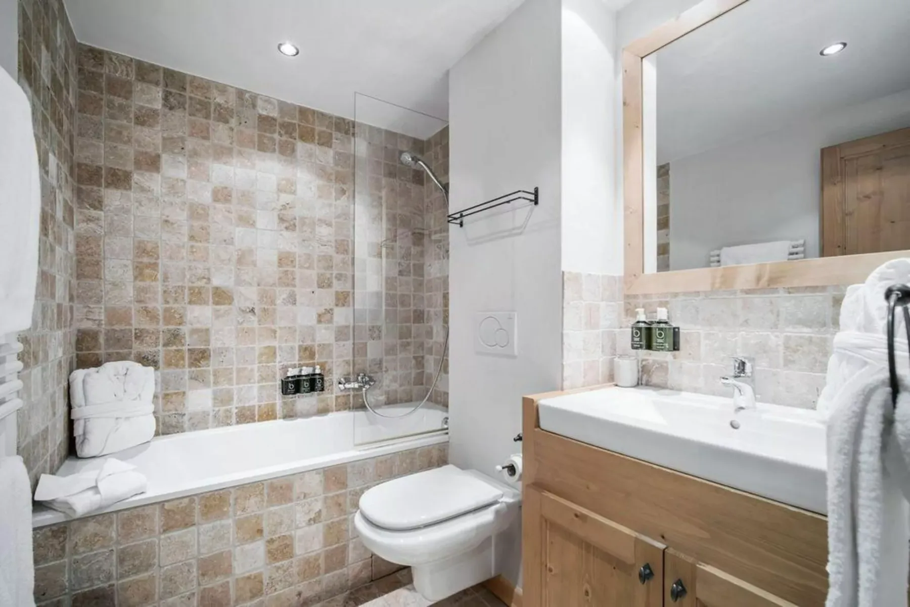 A tiled bathroom with a bathtub, toilet, and sink.