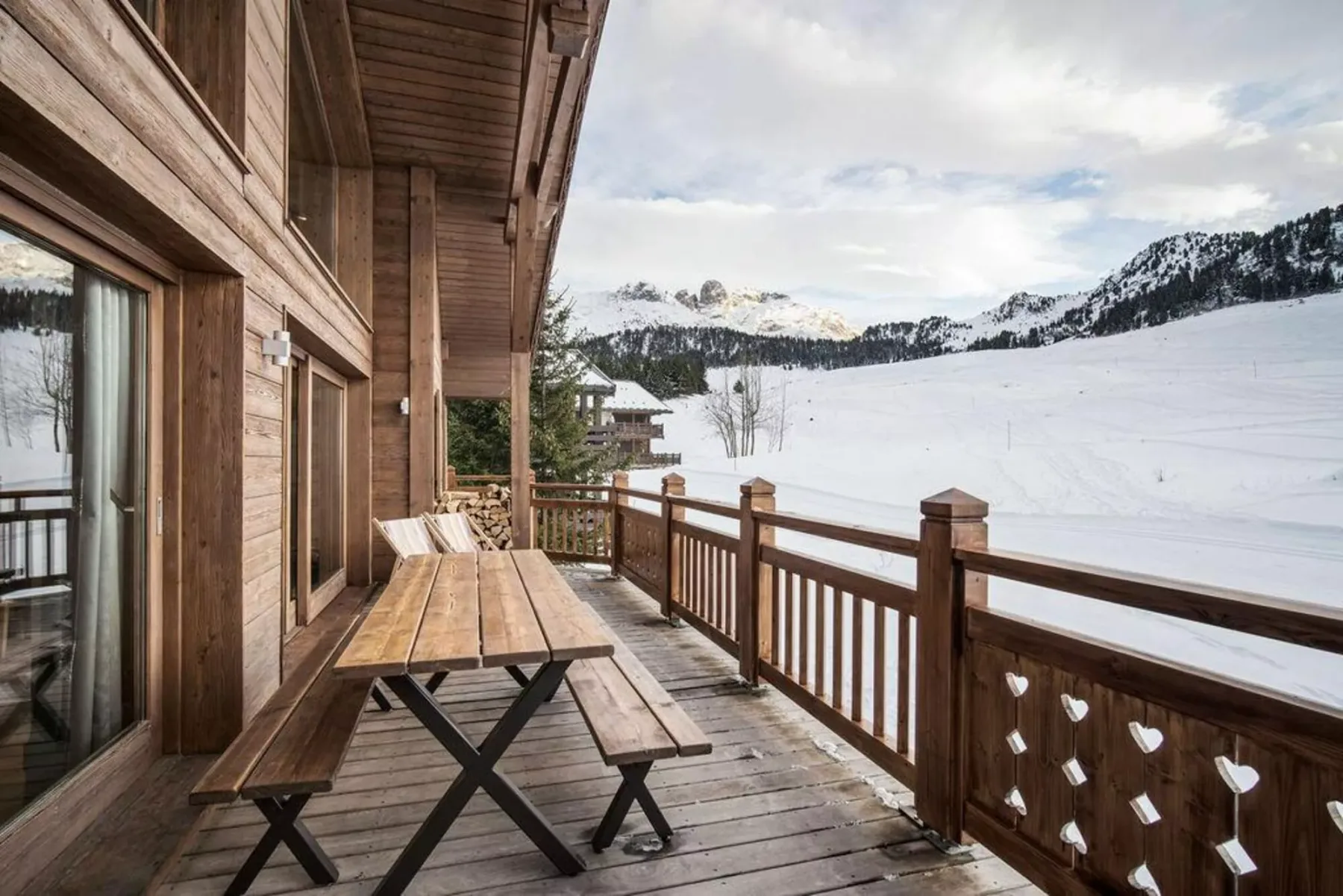 A wooden deck with a picnic table overlooks a snow-covered mountain landscape.
