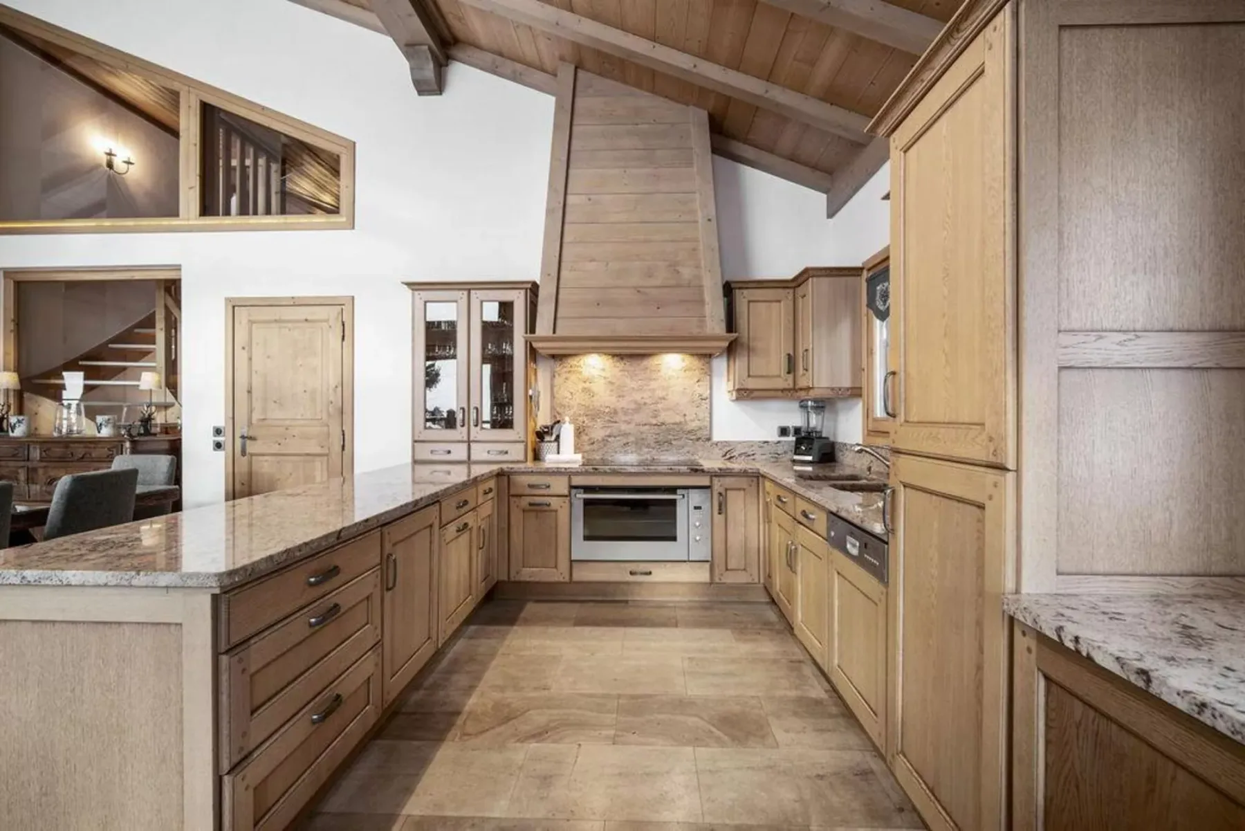 A spacious kitchen with wooden cabinets, a central cooking area, and a stone countertop.