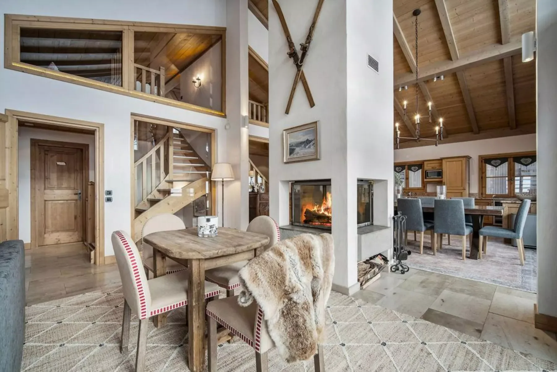 A rustic dining area with a wooden table beside a lit fireplace.