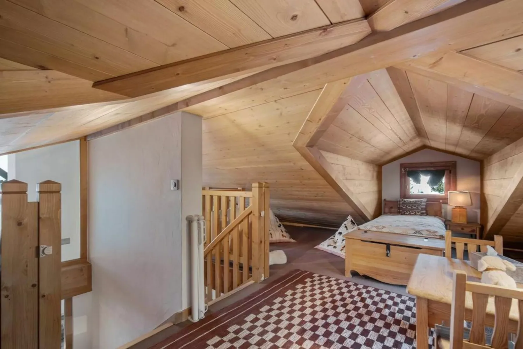 A wood-paneled attic bedroom with a bed and a patterned rug.
