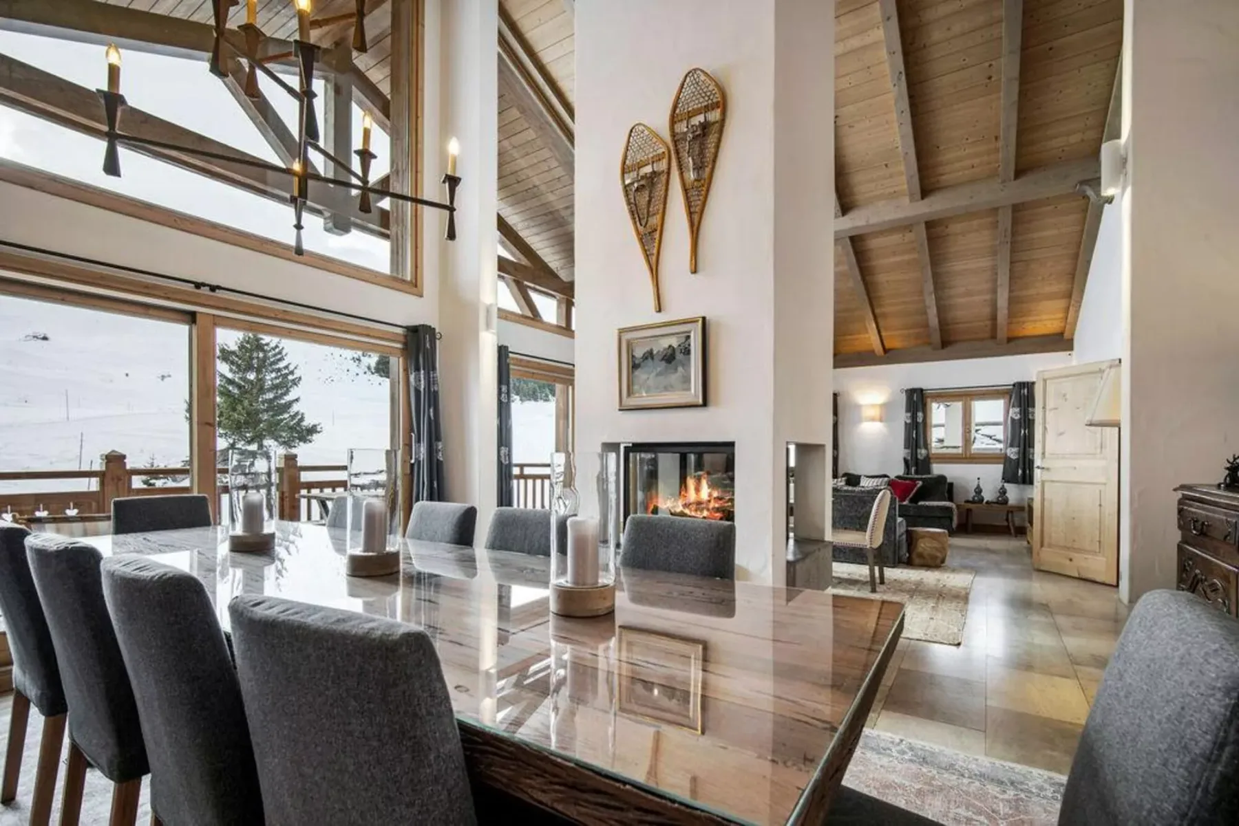 A bright dining area with a long table and a fireplace in the adjoining living space.