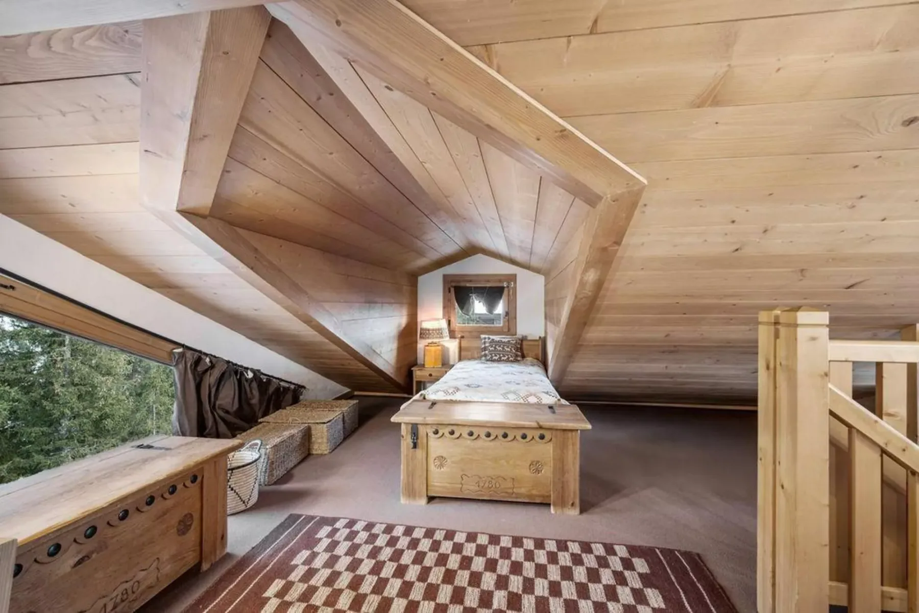 A wood-paneled attic bedroom has a bed beneath the sloped ceiling.
