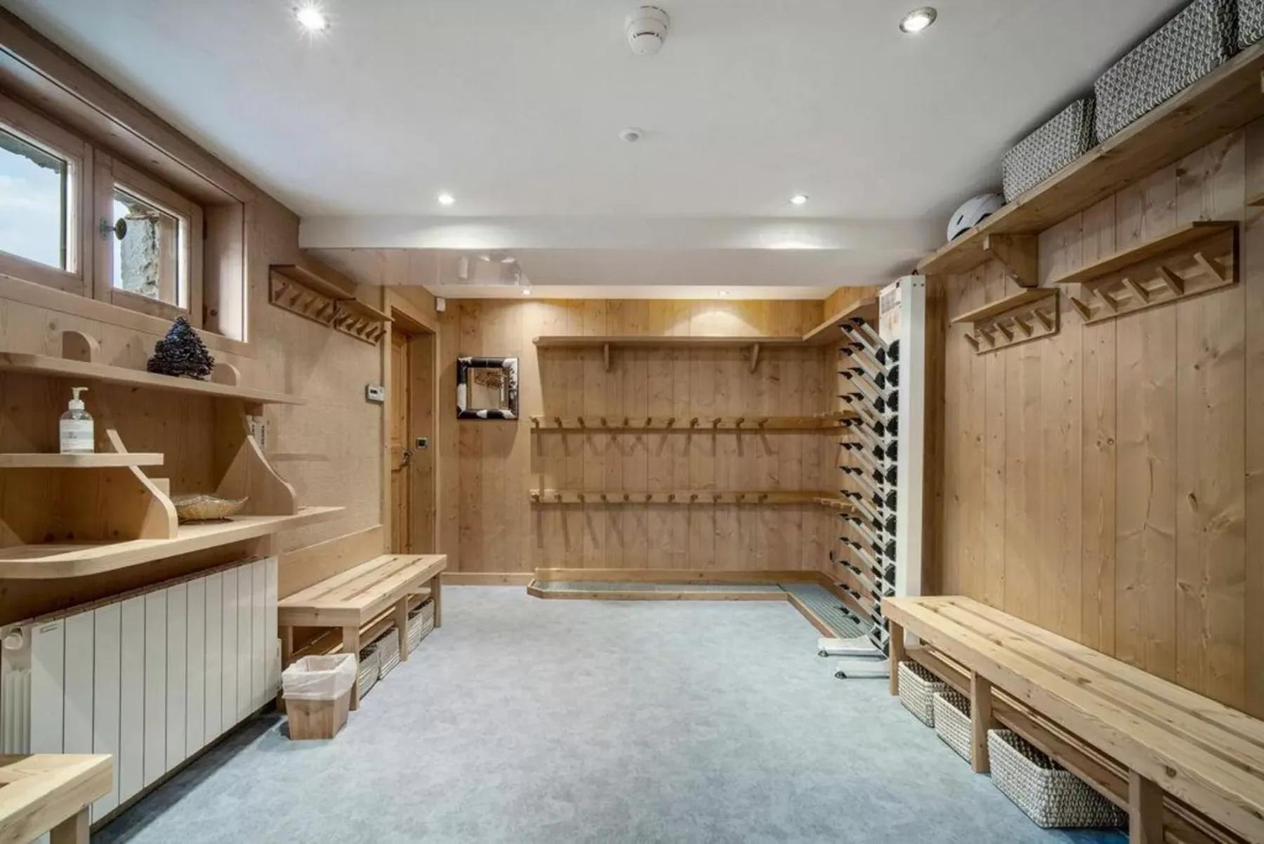 A wood-paneled changing room with benches and wall hooks.