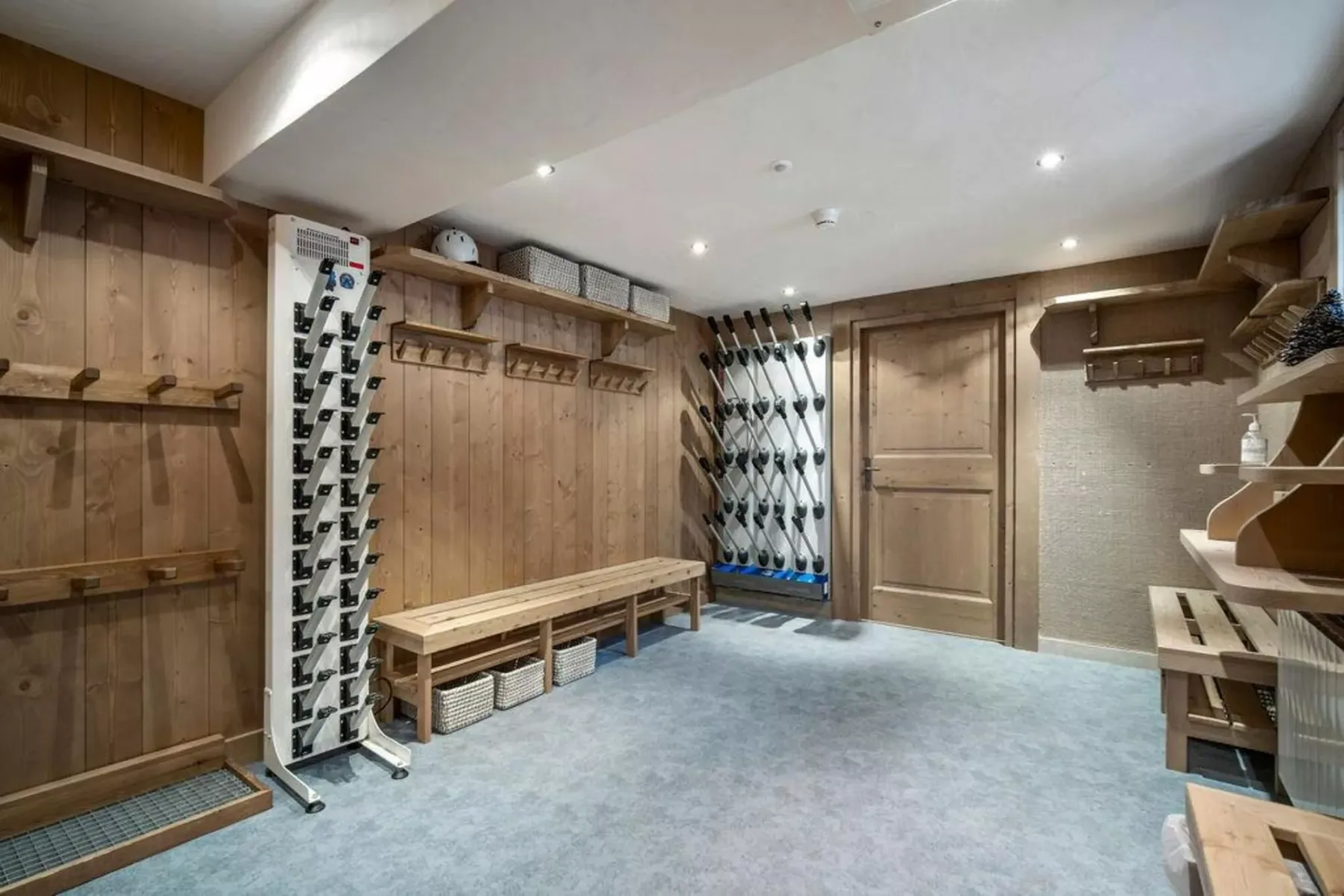 A wood-paneled room with benches, coat hooks, and several ski racks.