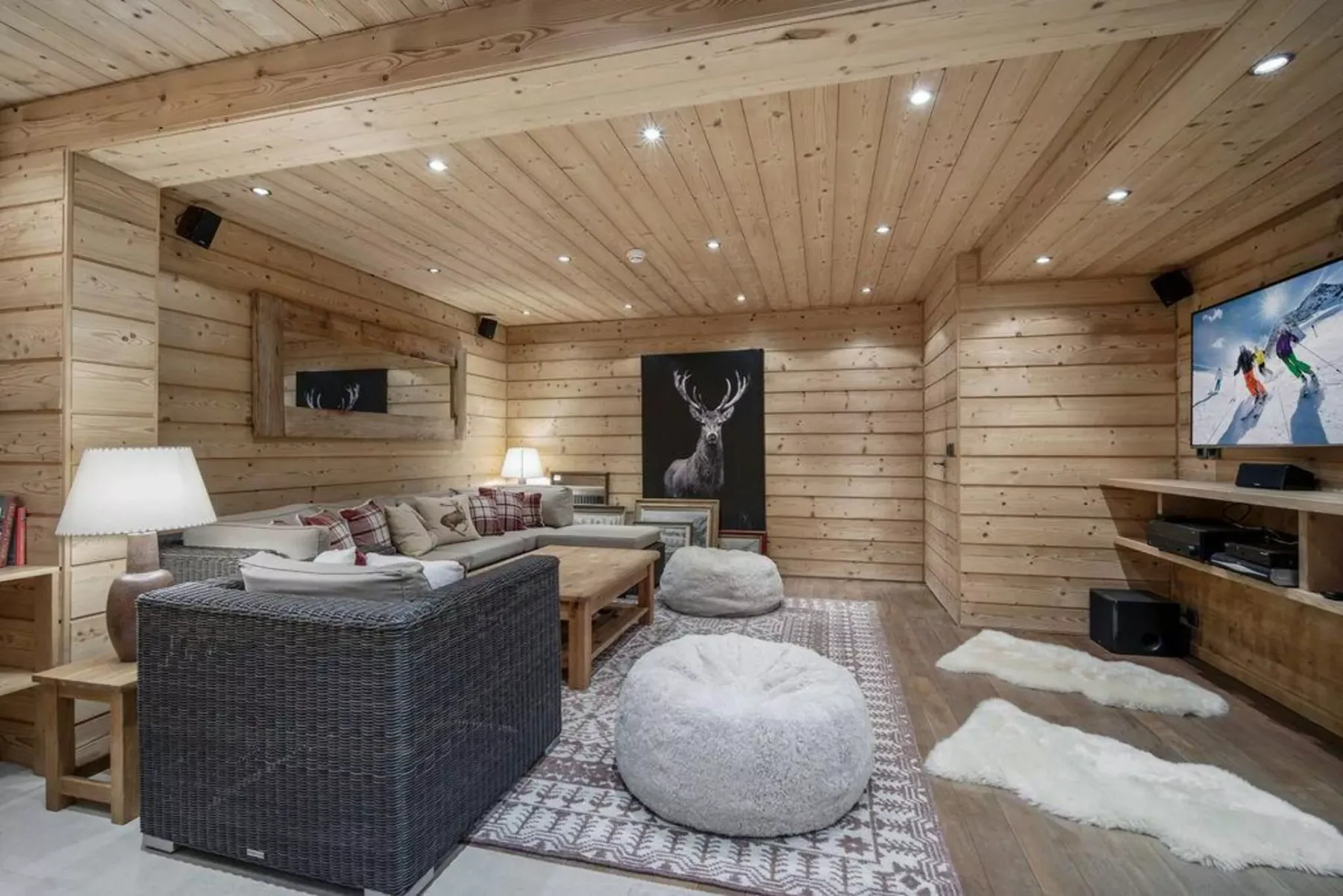 A wood-paneled living room with seating, a television, and a patterned rug.