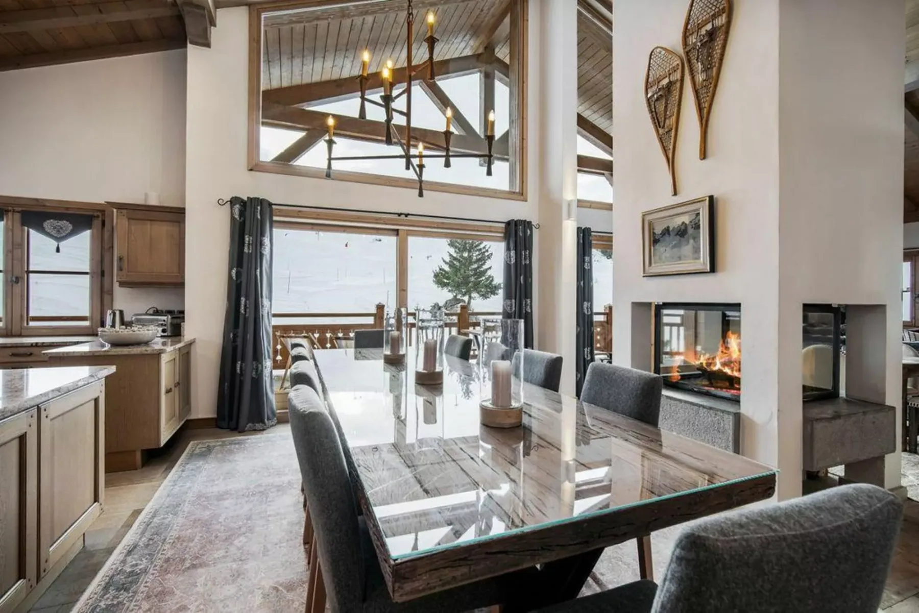 A dining area beside the kitchen and a fireplace, with large glass doors opening to a deck.