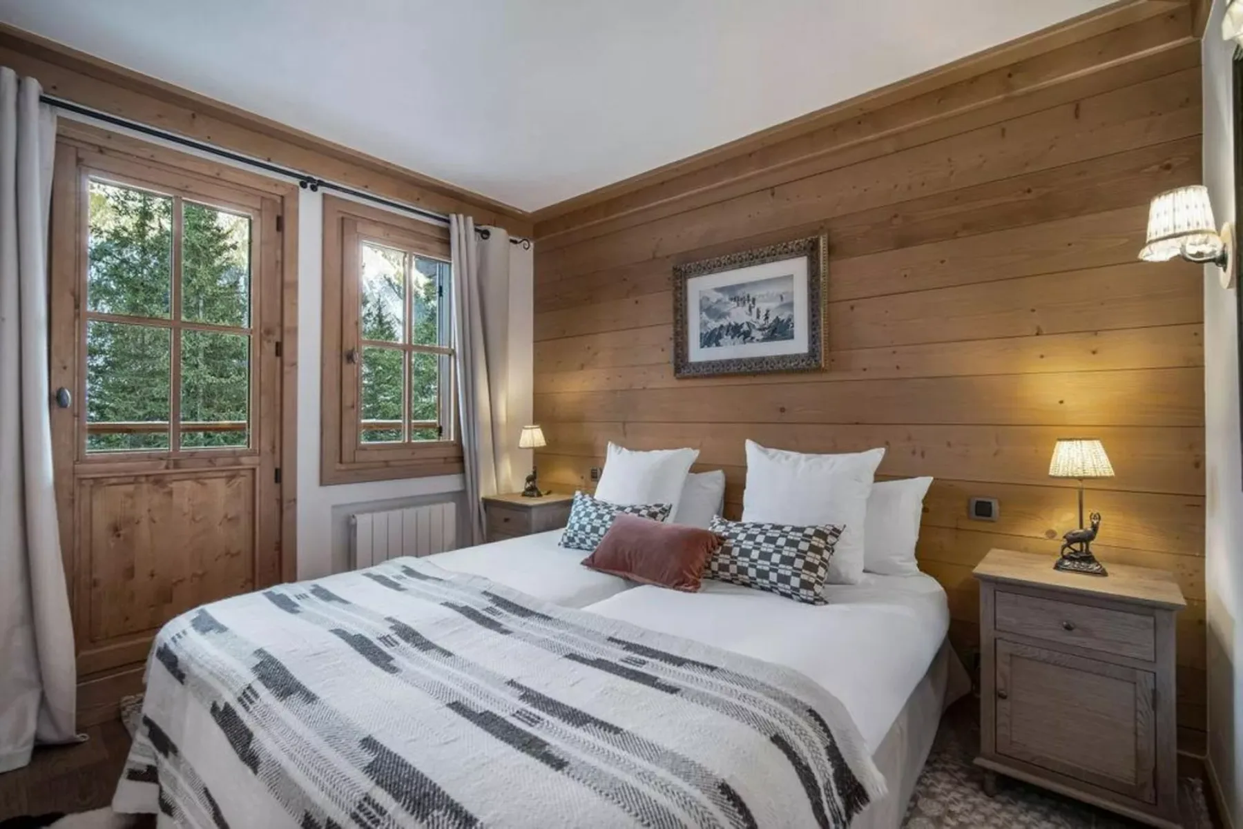 A bedroom with a double bed, bedside tables, and wood-paneled walls.
