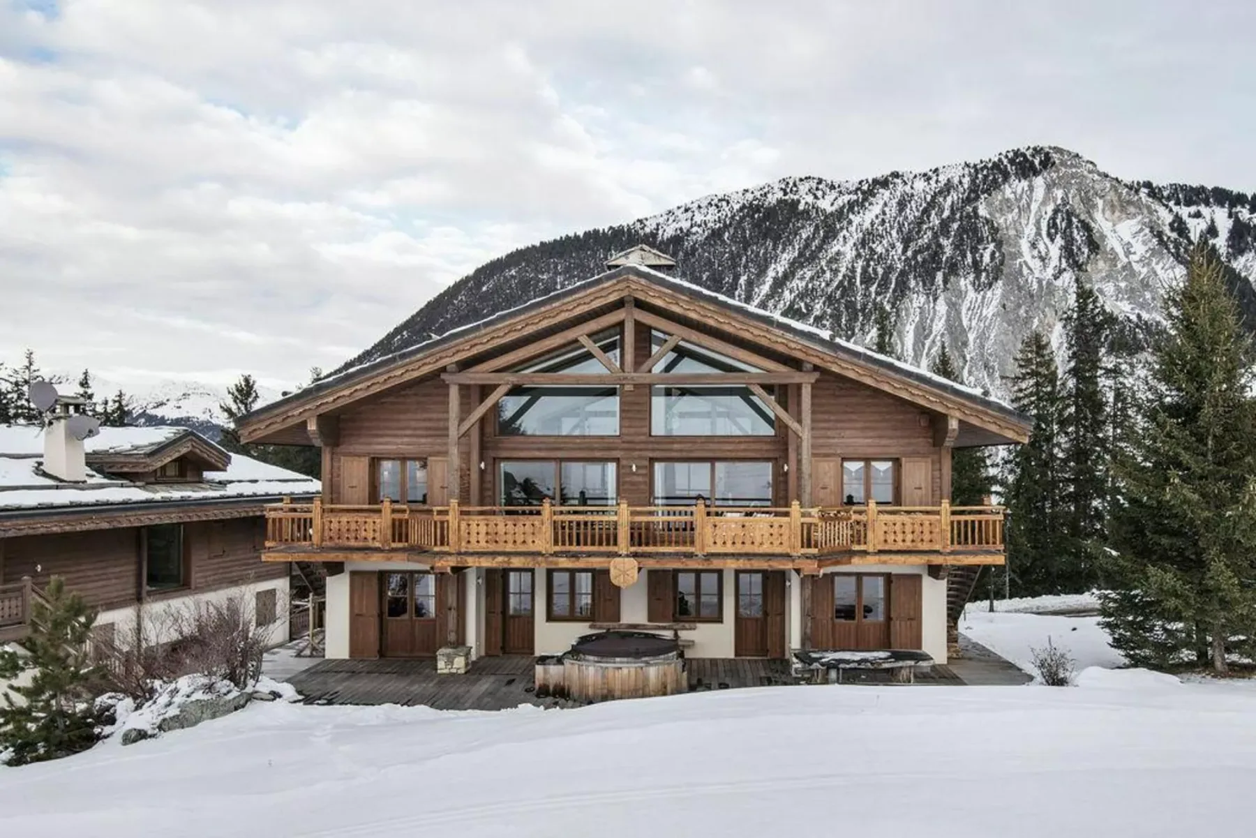 A large wooden chalet stands in a snowy mountain landscape.