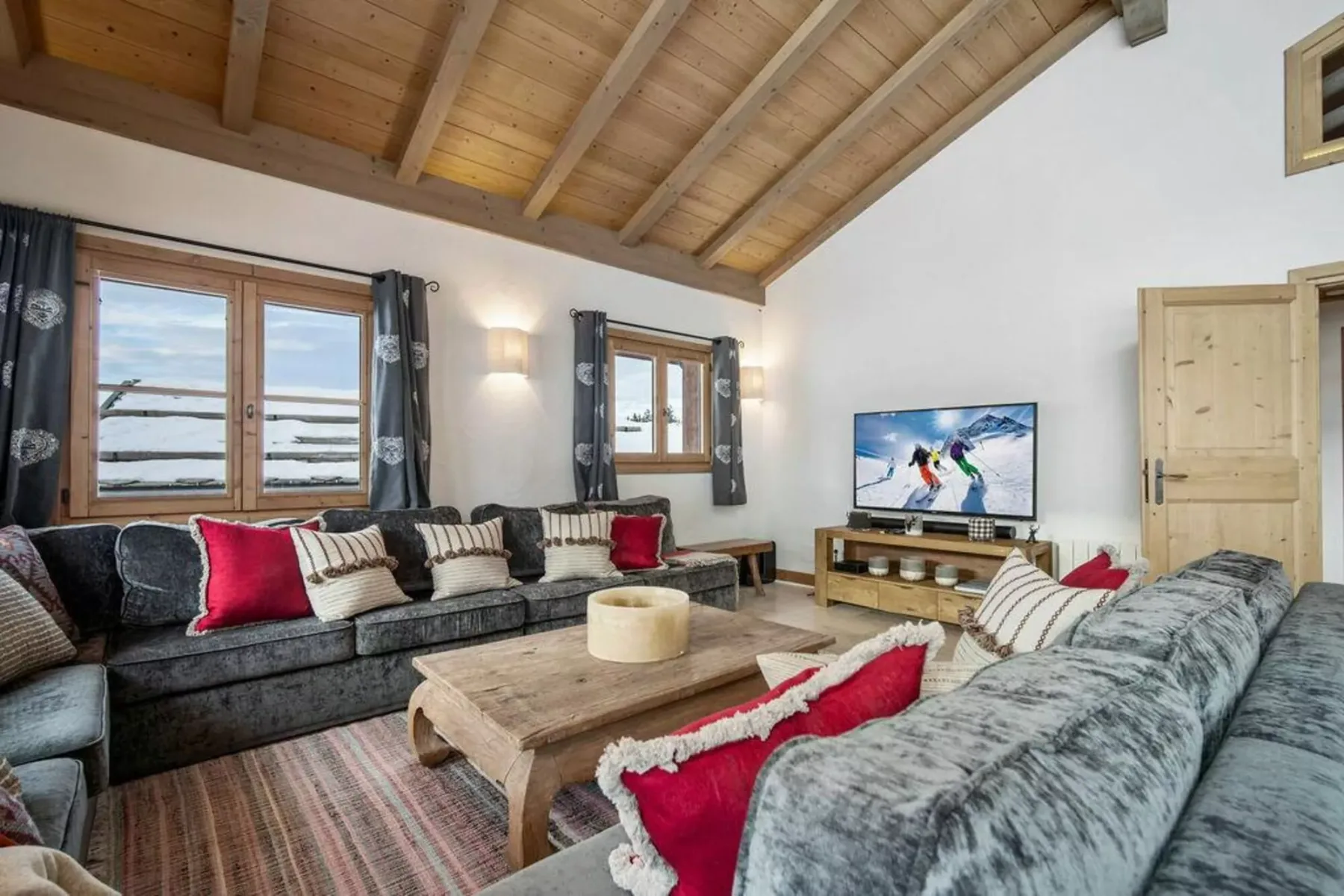A living room with seating around a wooden coffee table and a television.