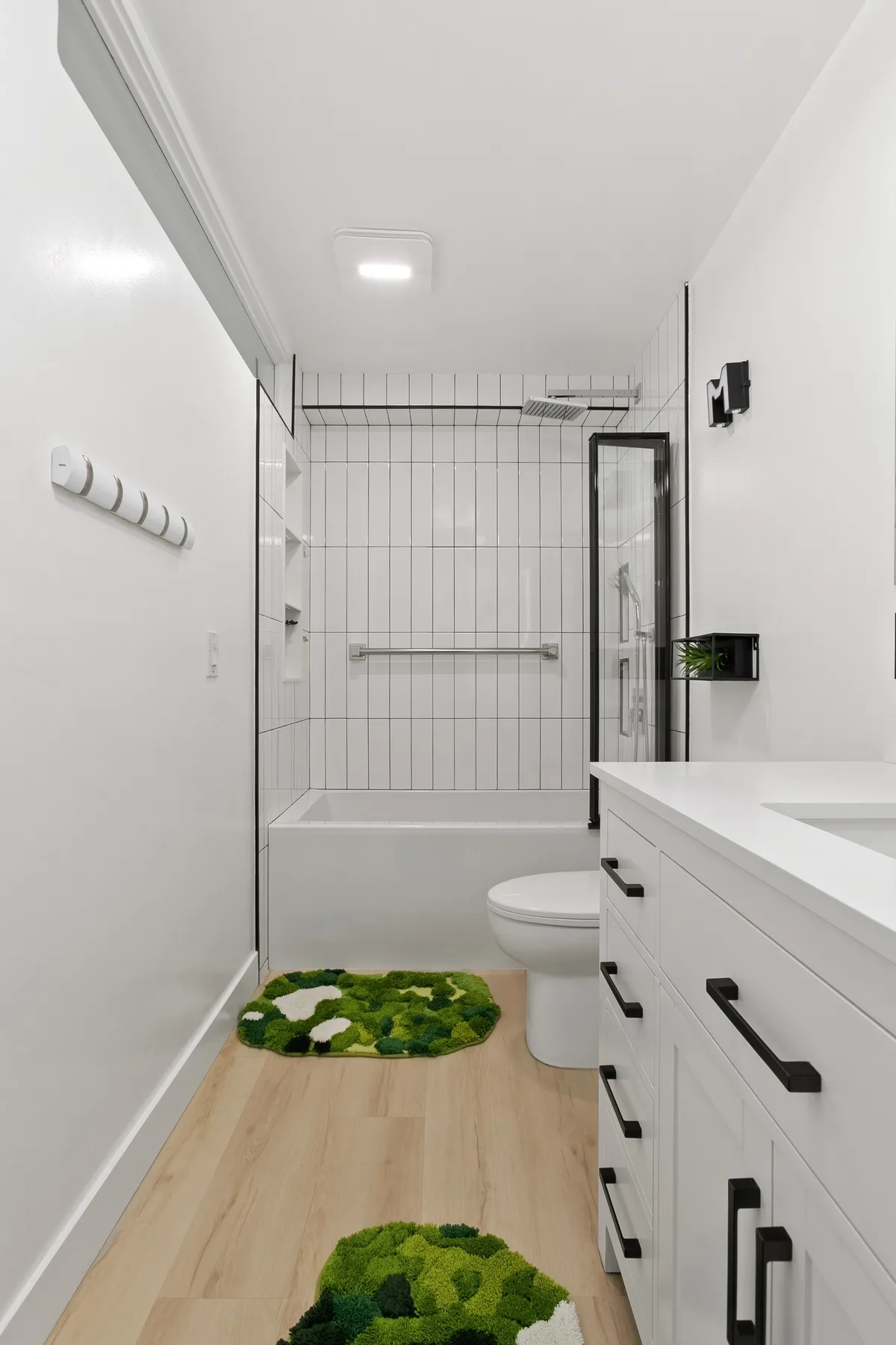 Un baño luminoso con bañera, mampara de ducha de vidrio y tocador blanco.