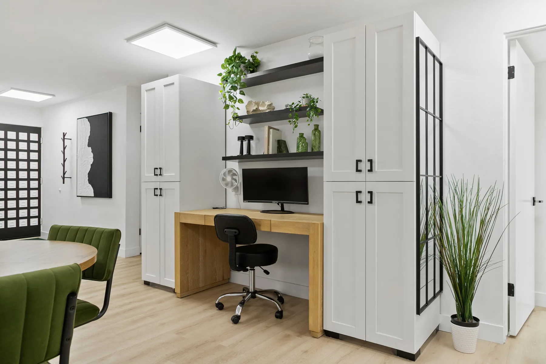 Una habitación luminosa con escritorio integrado, estantes y zona de comedor.