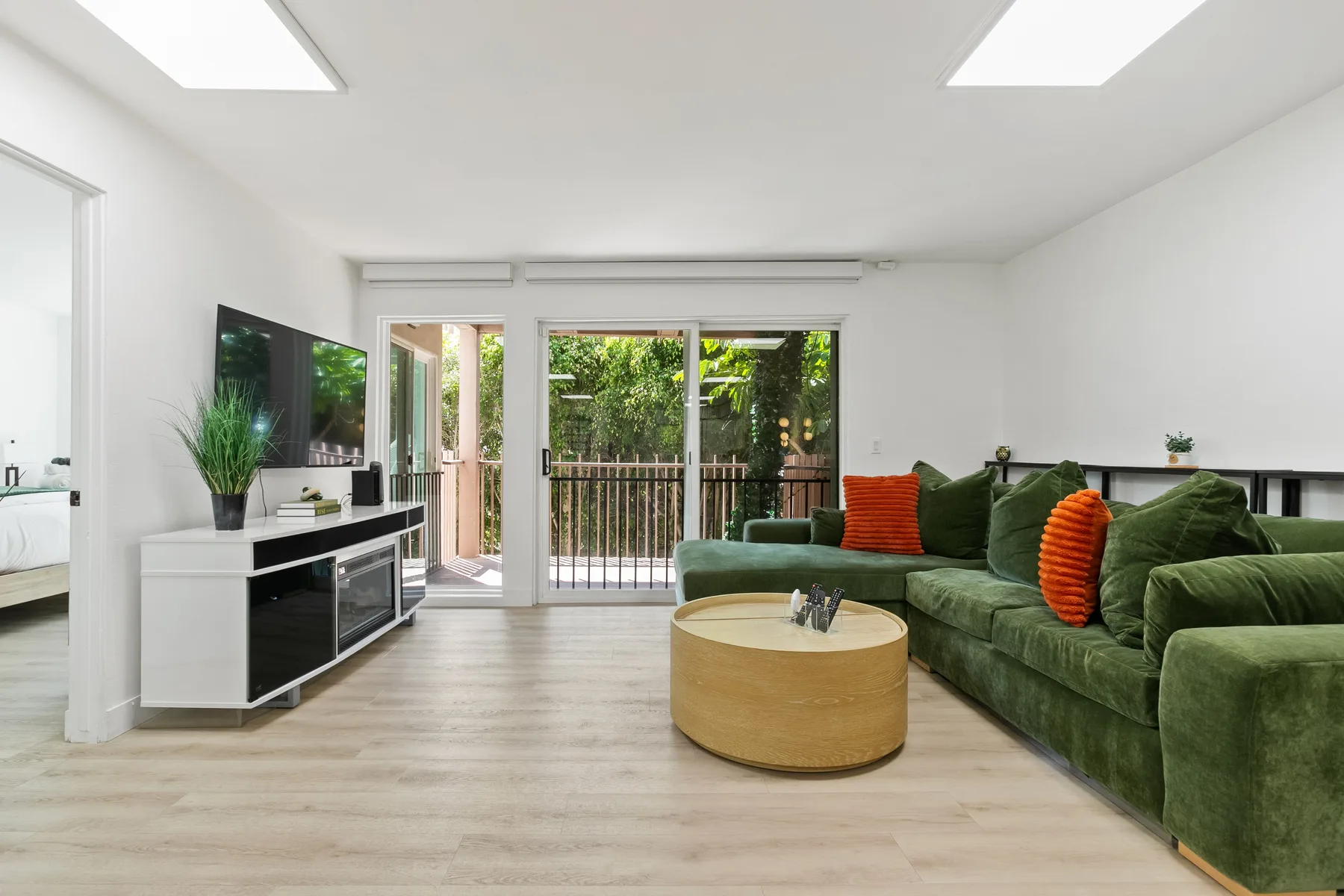 Una sala luminosa con asientos verdes y puertas de vidrio que dan a un jardín.