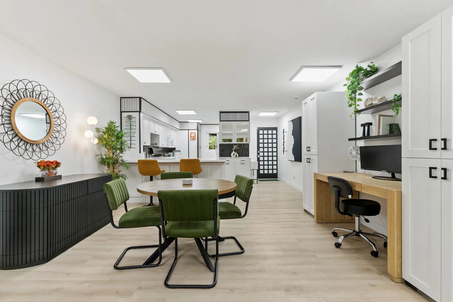 Una luminosa cocina y comedor de planta abierta con asientos verdes y una encimera larga.