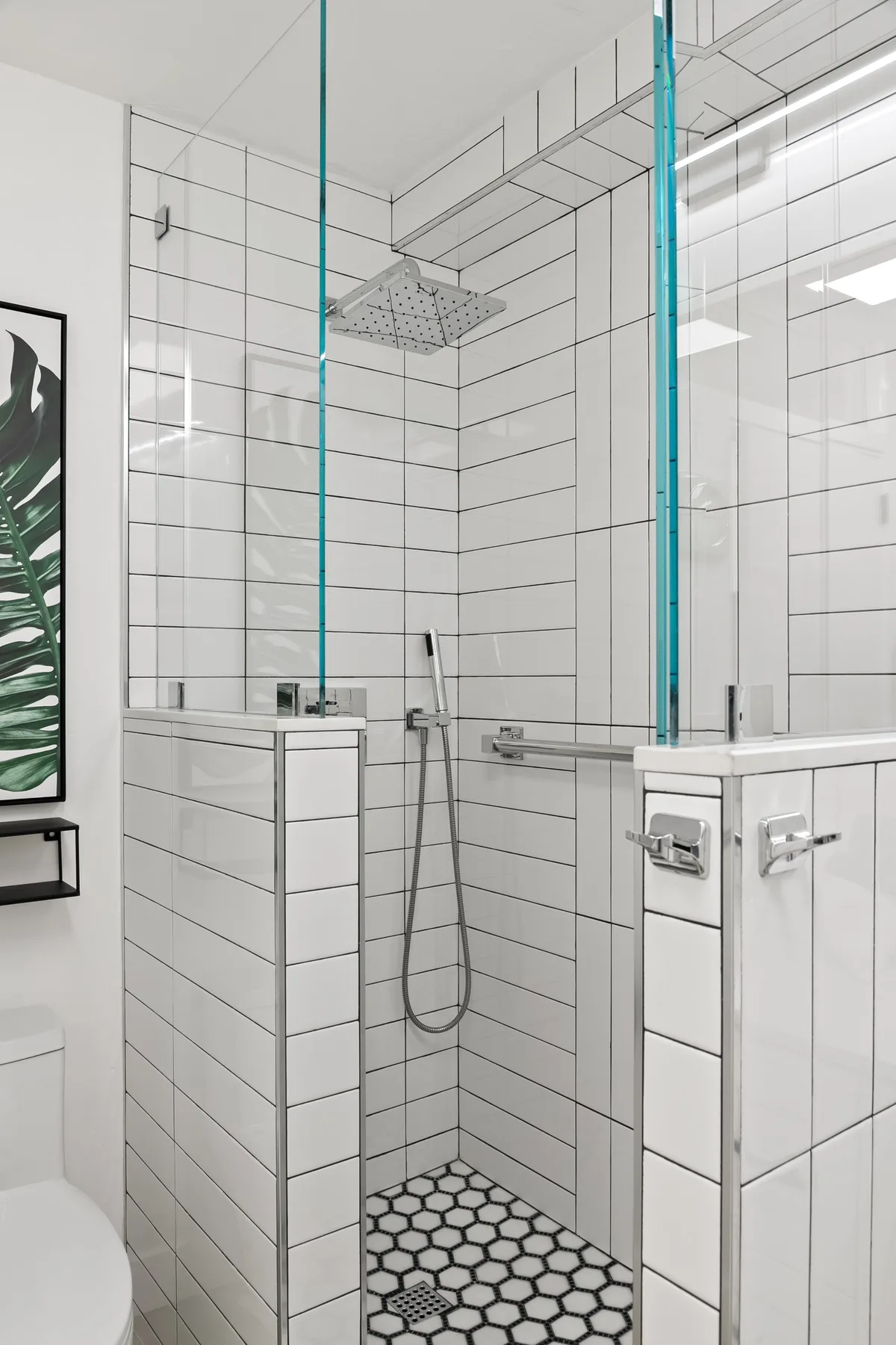 Una ducha de baño alicatada con rociador de lluvia y suelo estampado.