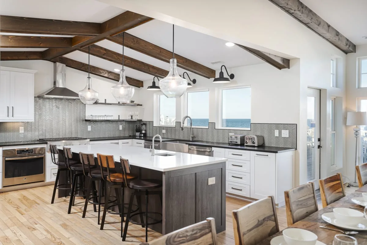 A bright kitchen with a large island, bar seating, and pendant lights.