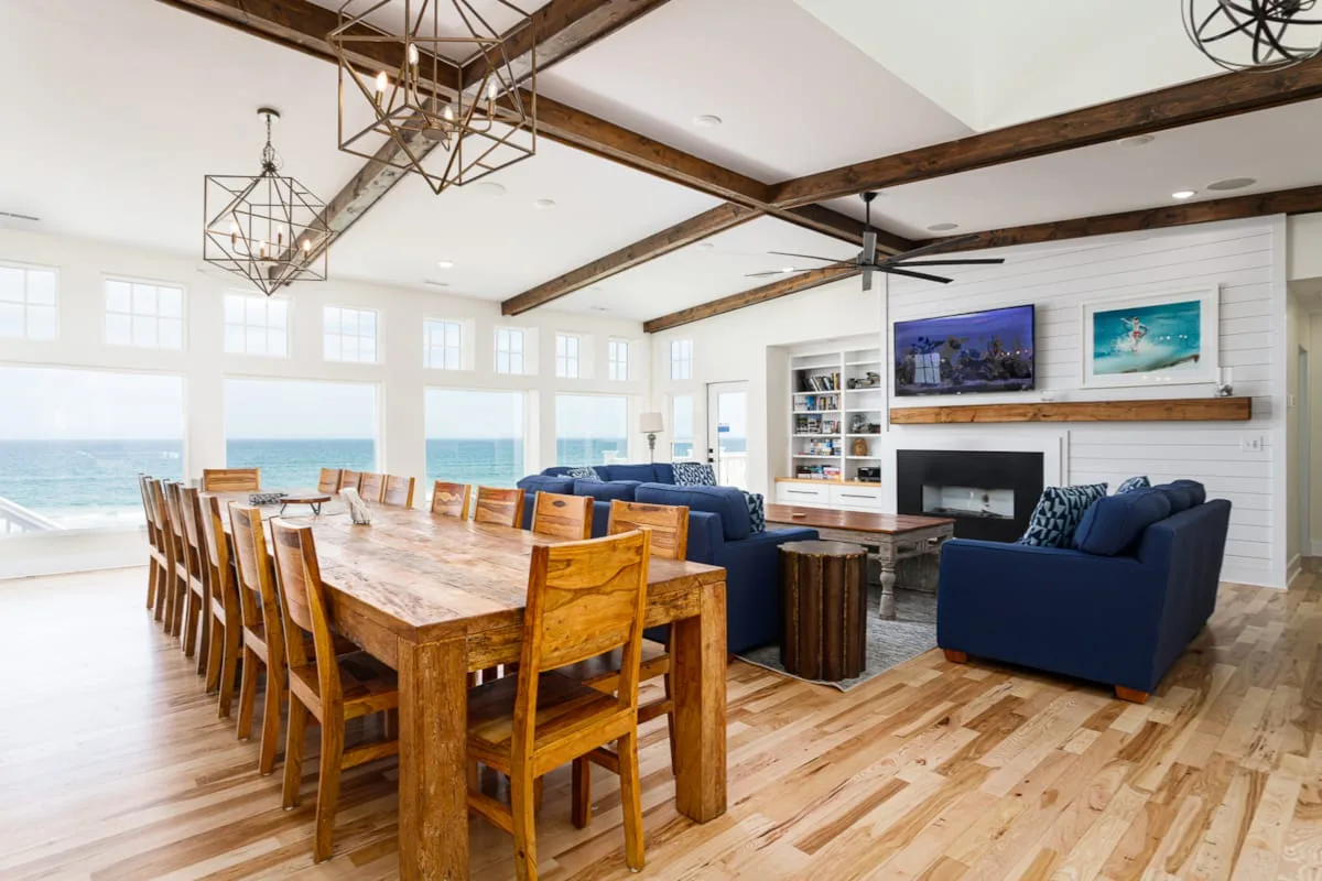 A bright open-plan living and dining area with large windows overlooking the water.