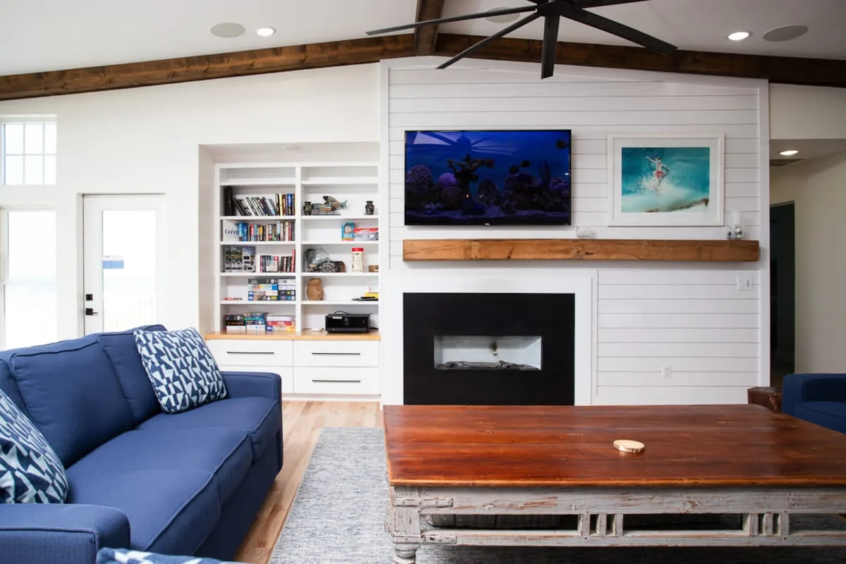 A bright living room with blue seating, a fireplace, and a wooden coffee table.