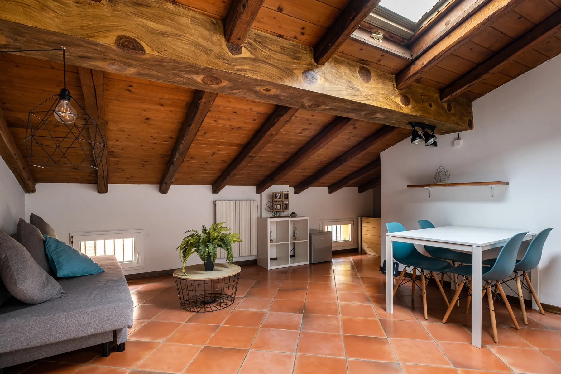 Una amplia sala y comedor tiene un techo de madera y baldosas de terracota.