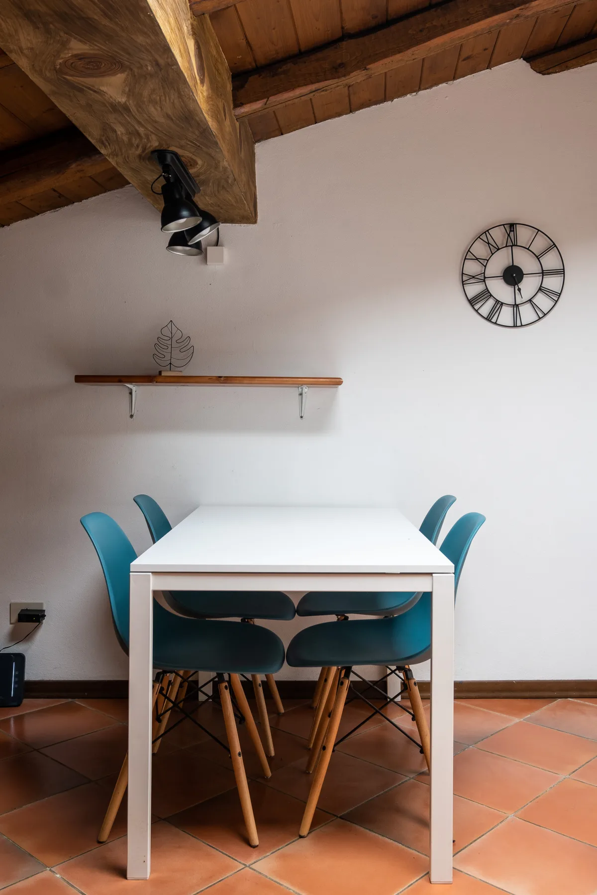 Un comedor con una mesa blanca y asientos azules bajo un techo de madera.