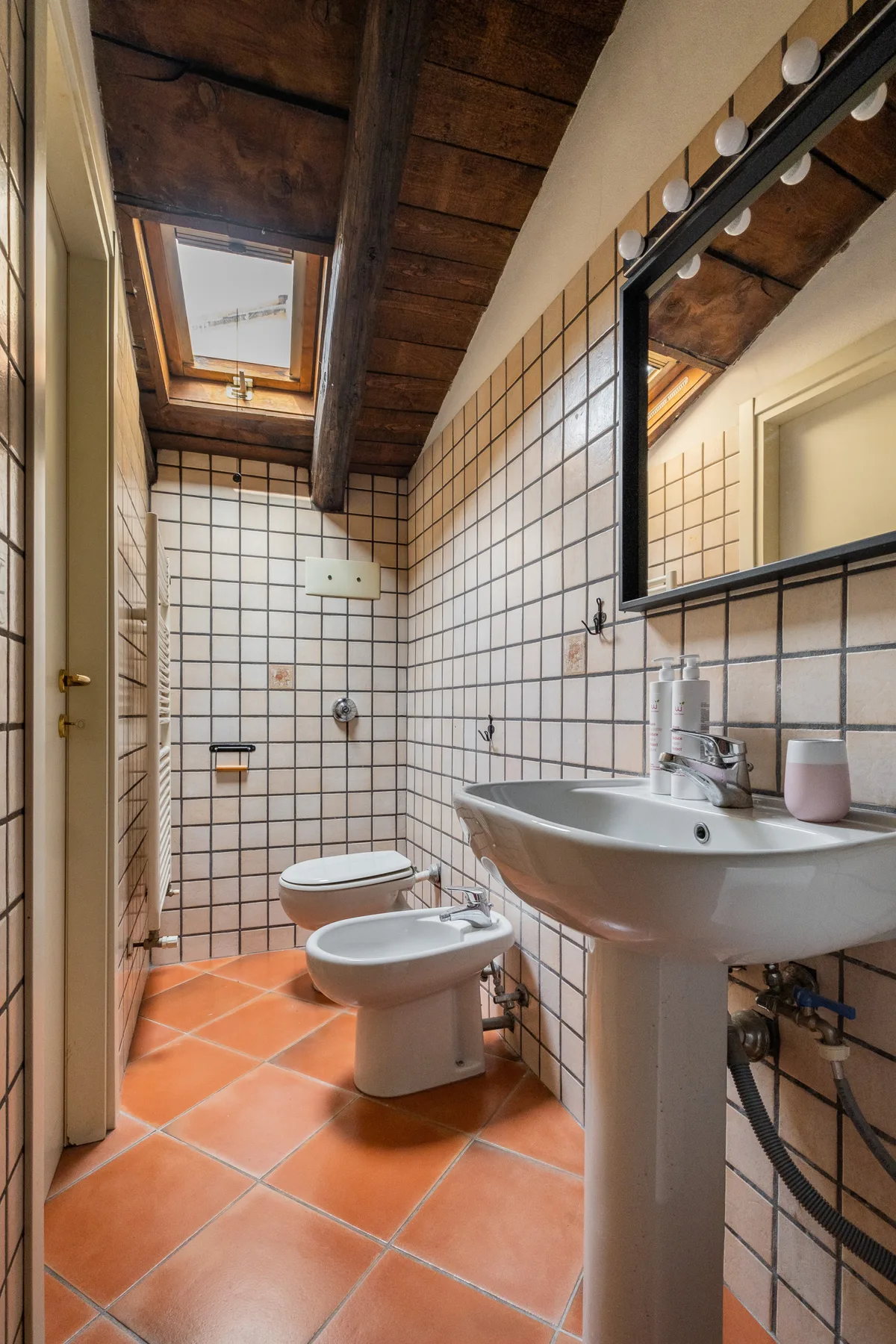 Un baño alicatado con lavabo, inodoro, bidé y tragaluz.