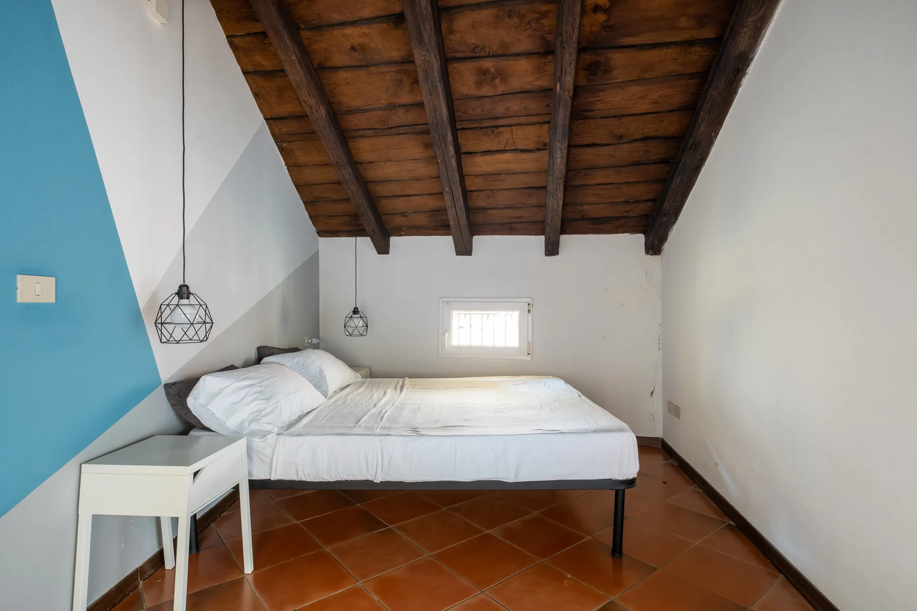 Un dormitorio con una cama bajo vigas de madera expuestas.