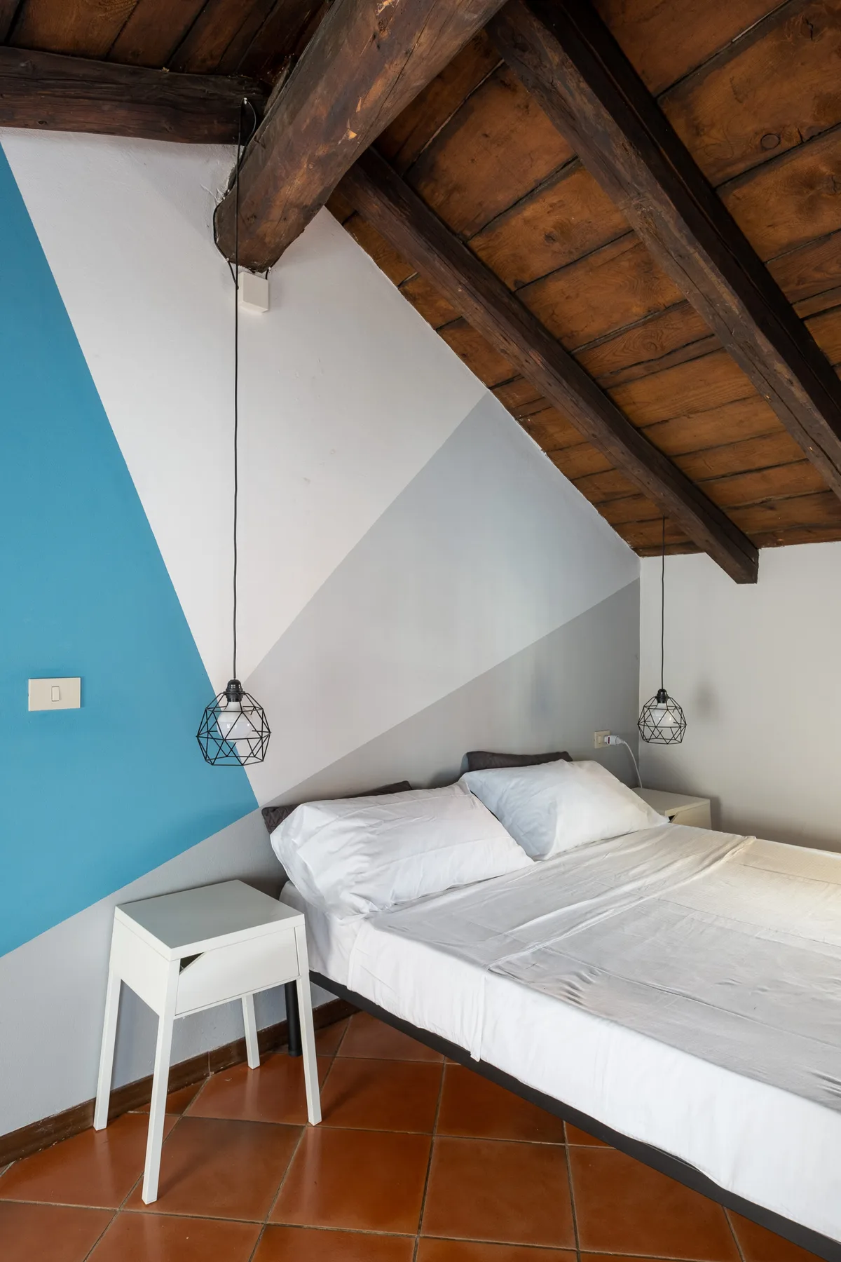 Un dormitorio con una cama bajo vigas de madera vistas y paredes de colores.