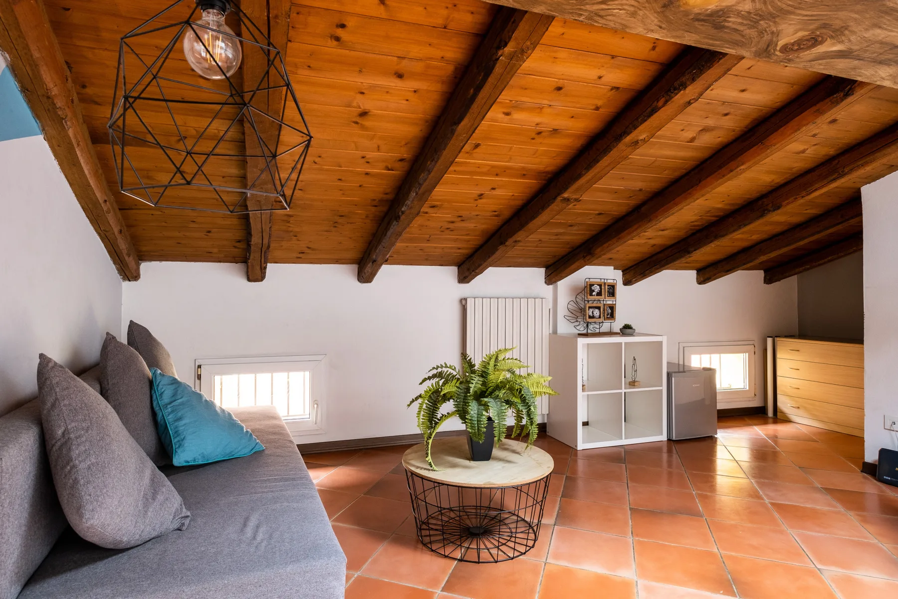 Una sala de estar luminosa con asientos, una mesa de centro y vigas de madera expuestas.