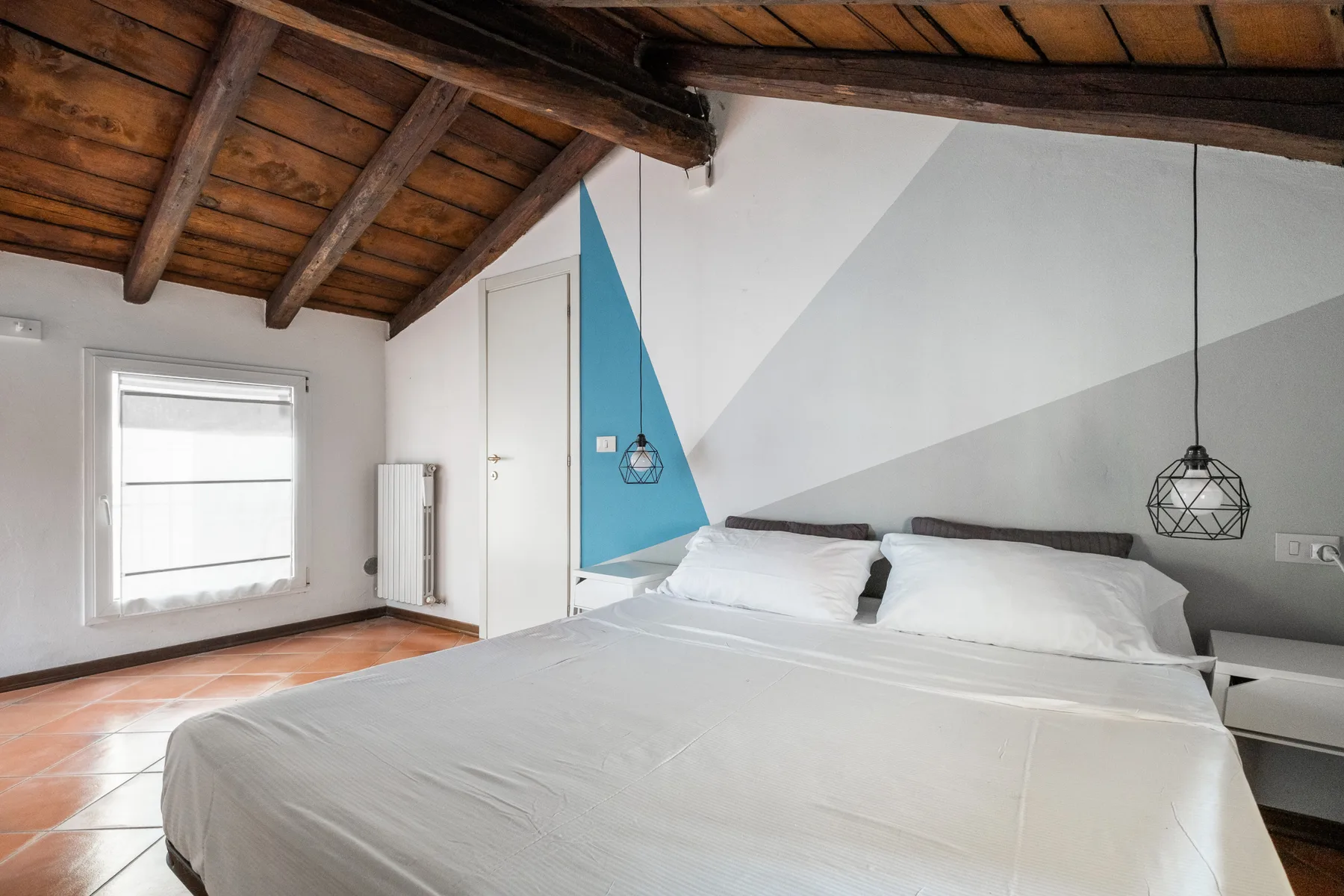 Un dormitorio con una cama grande bajo un techo inclinado de madera.