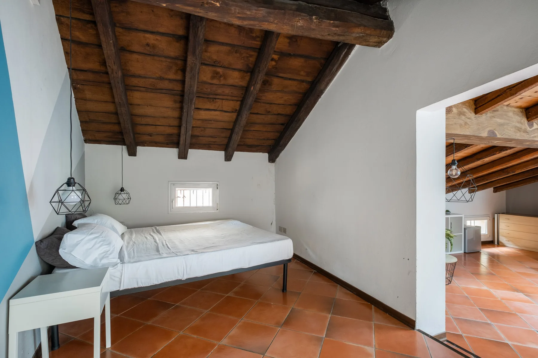 Un dormitorio con una cama baja bajo vigas de madera a la vista.
