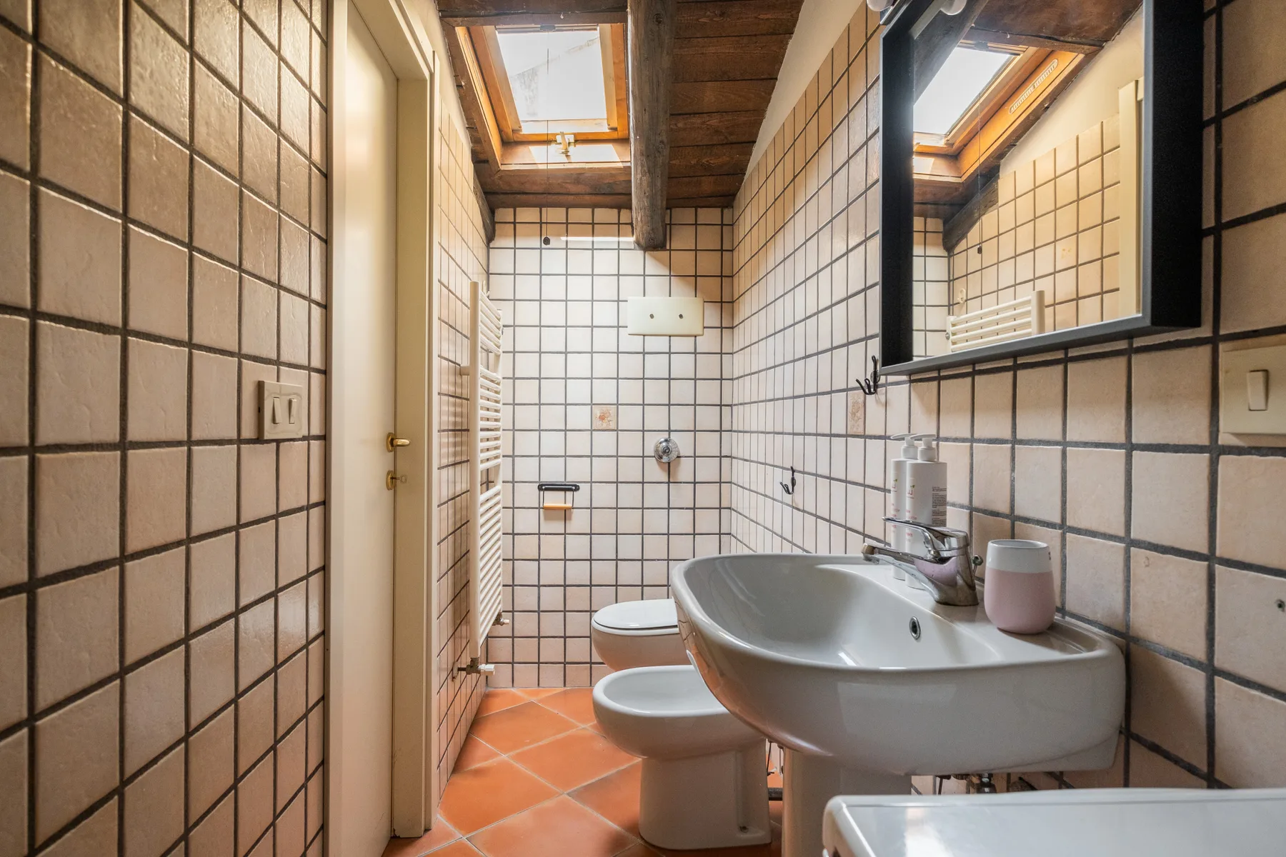 Un baño alicatado con lavabo, inodoro y tragaluz.