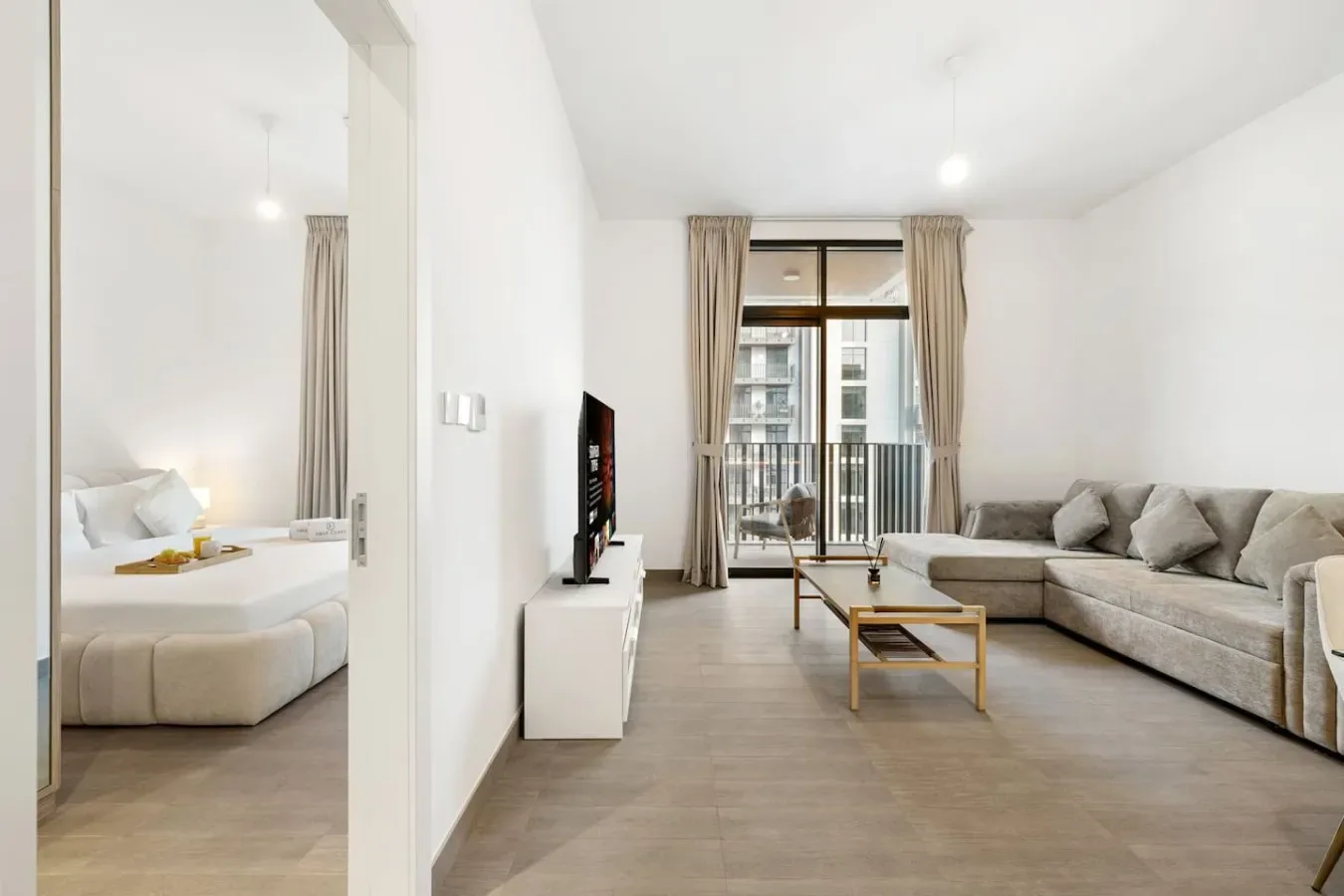 A bright living room with a sectional seating area beside a bedroom.